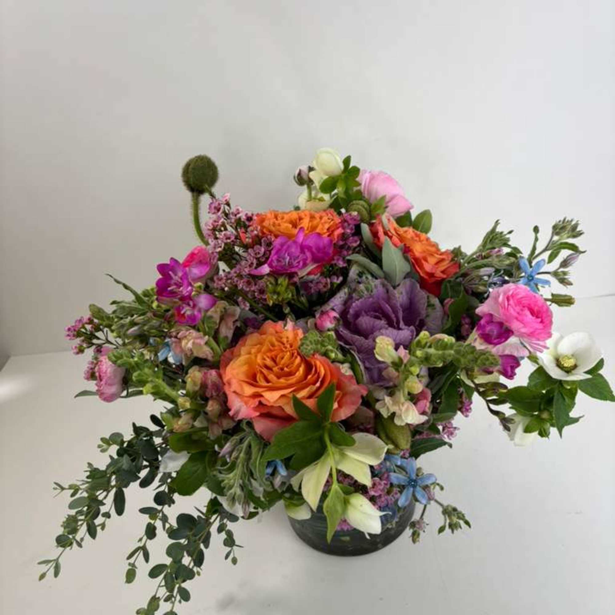 Mixed bouquet in a dark vase with orange, pink, purple, and white blooms