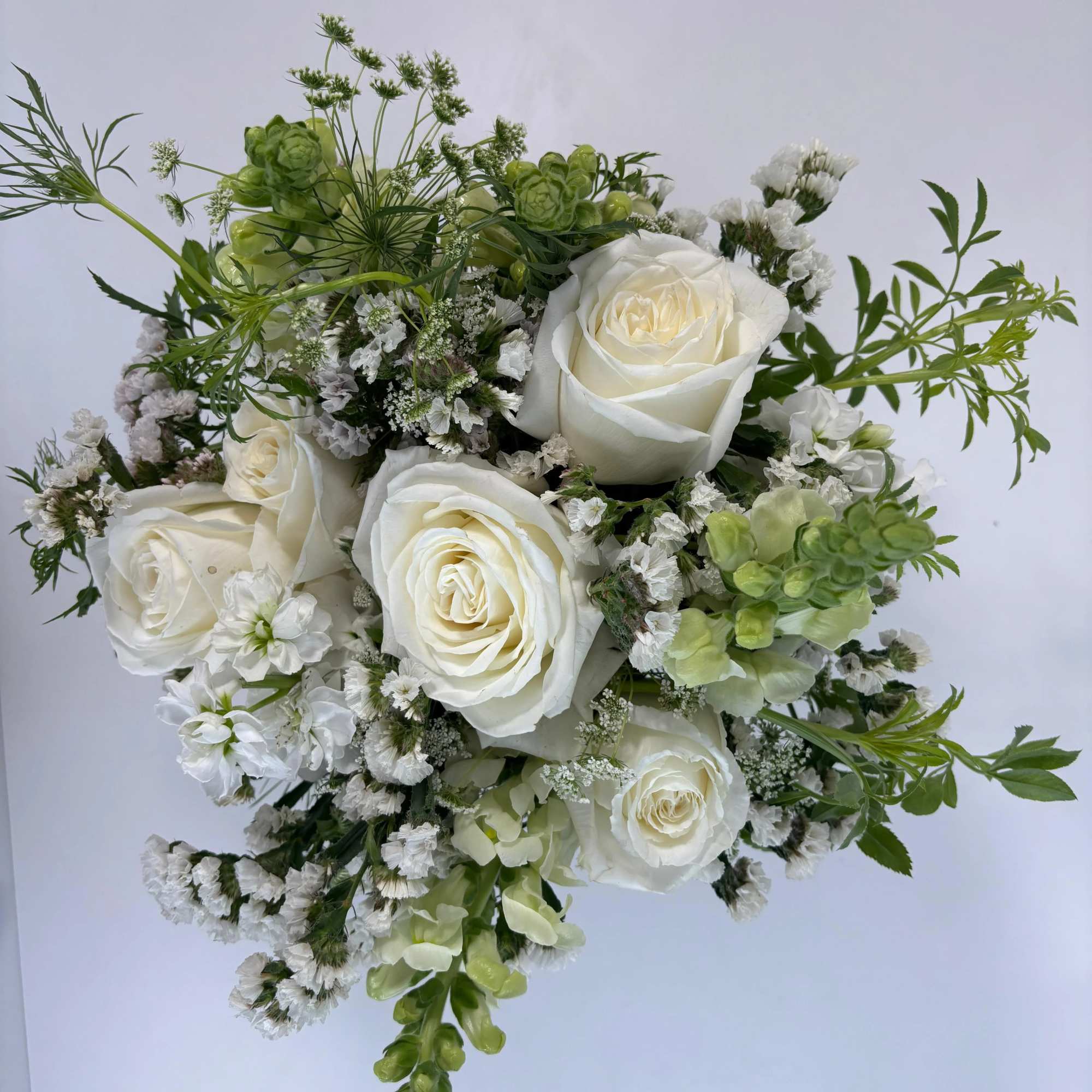 White rose bouquet with green accents and small white filler flowers
