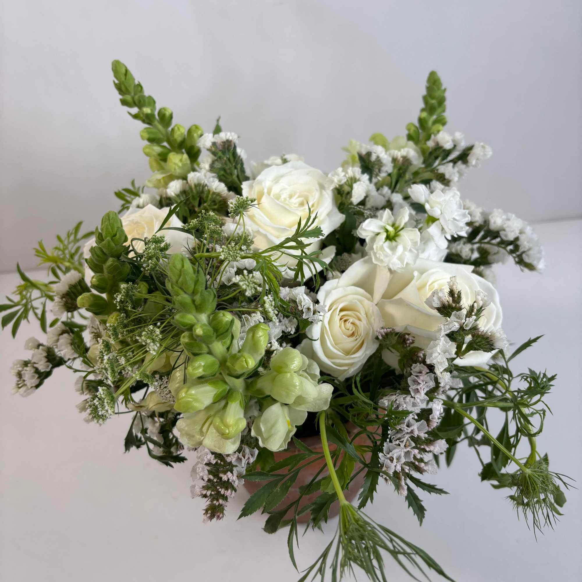 White roses and green-white flowers in a low bouquet