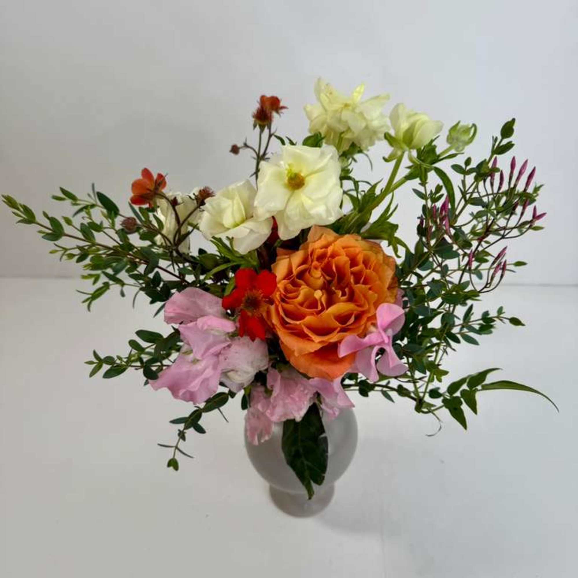 Mixed bouquet of orange, pink, and white flowers in a vase
