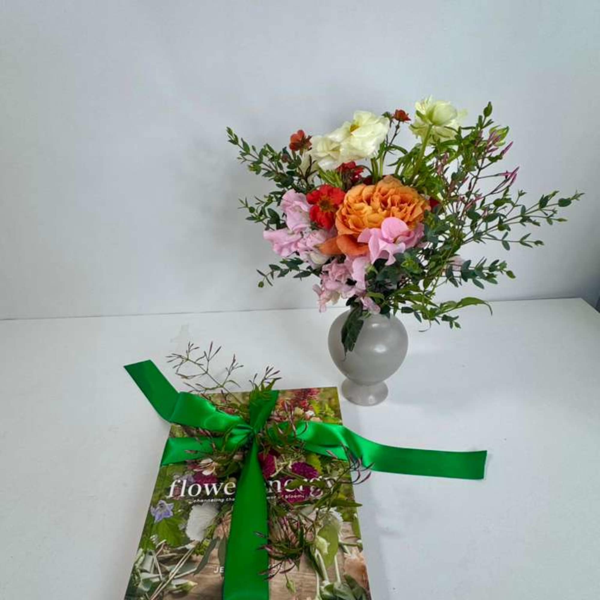 Mixed bouquet in a gray vase beside a ribbon-tied book