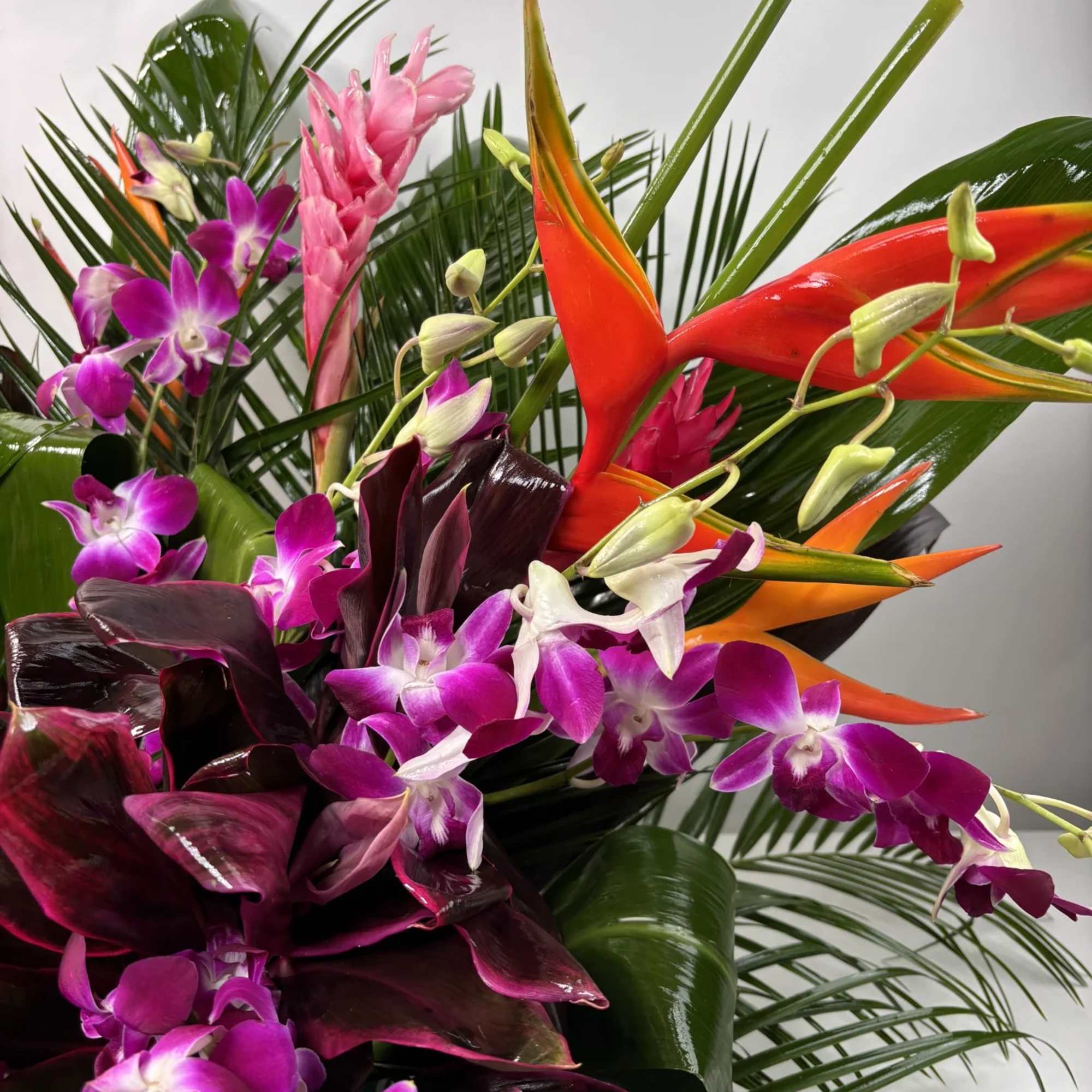 Tropical bouquet with purple orchids and orange bird of paradise flowers