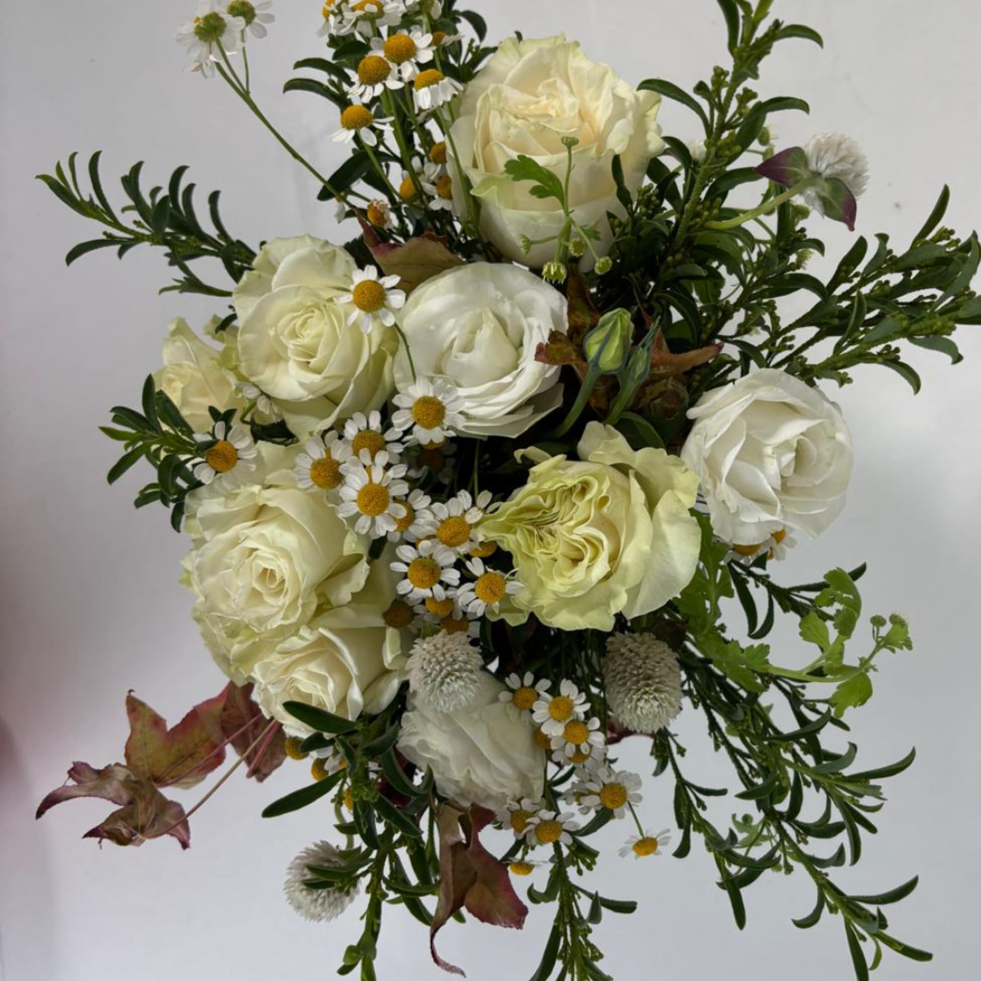 Bouquet of cream roses and small white daisies with greenery