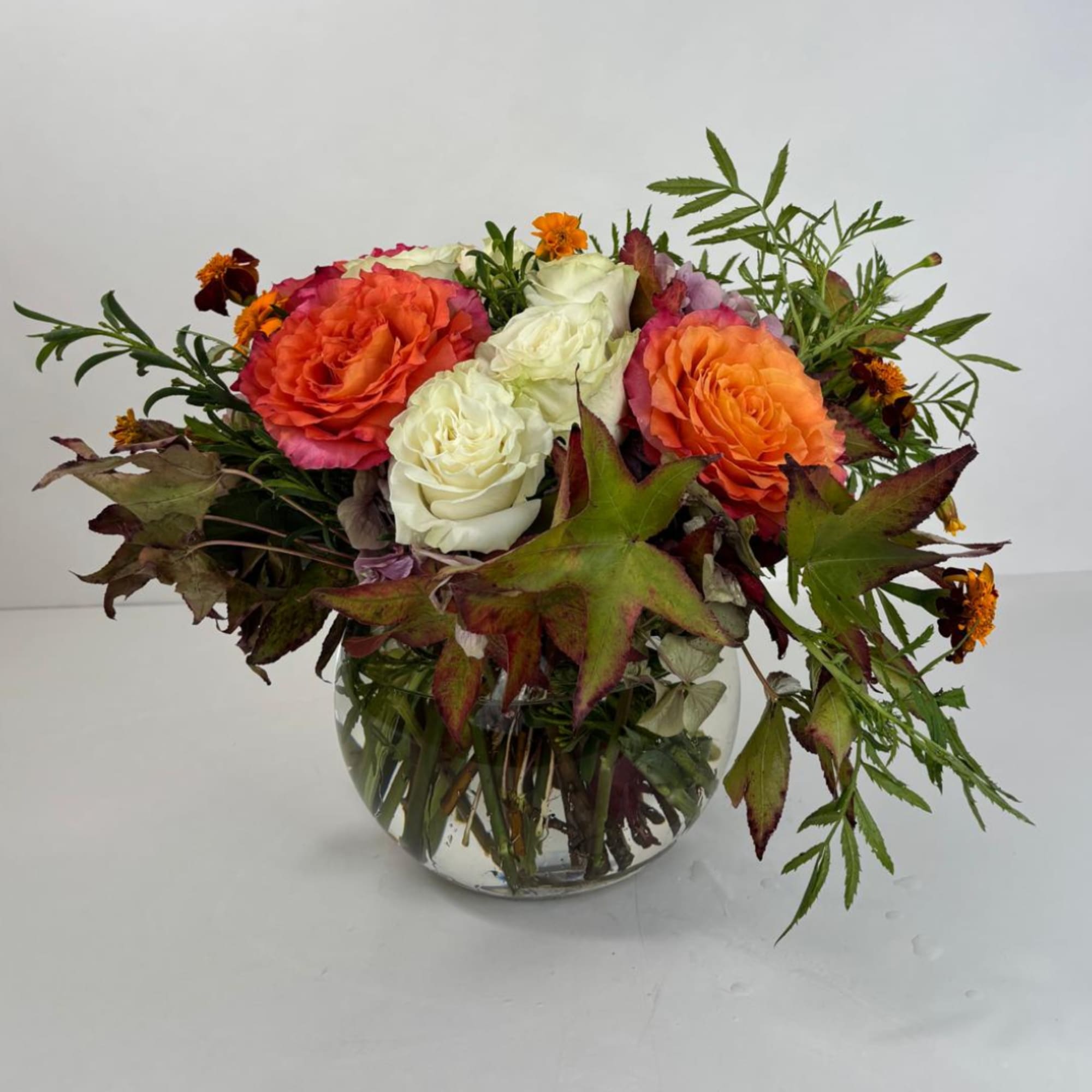 Mixed roses in a clear glass vase with autumn leaves