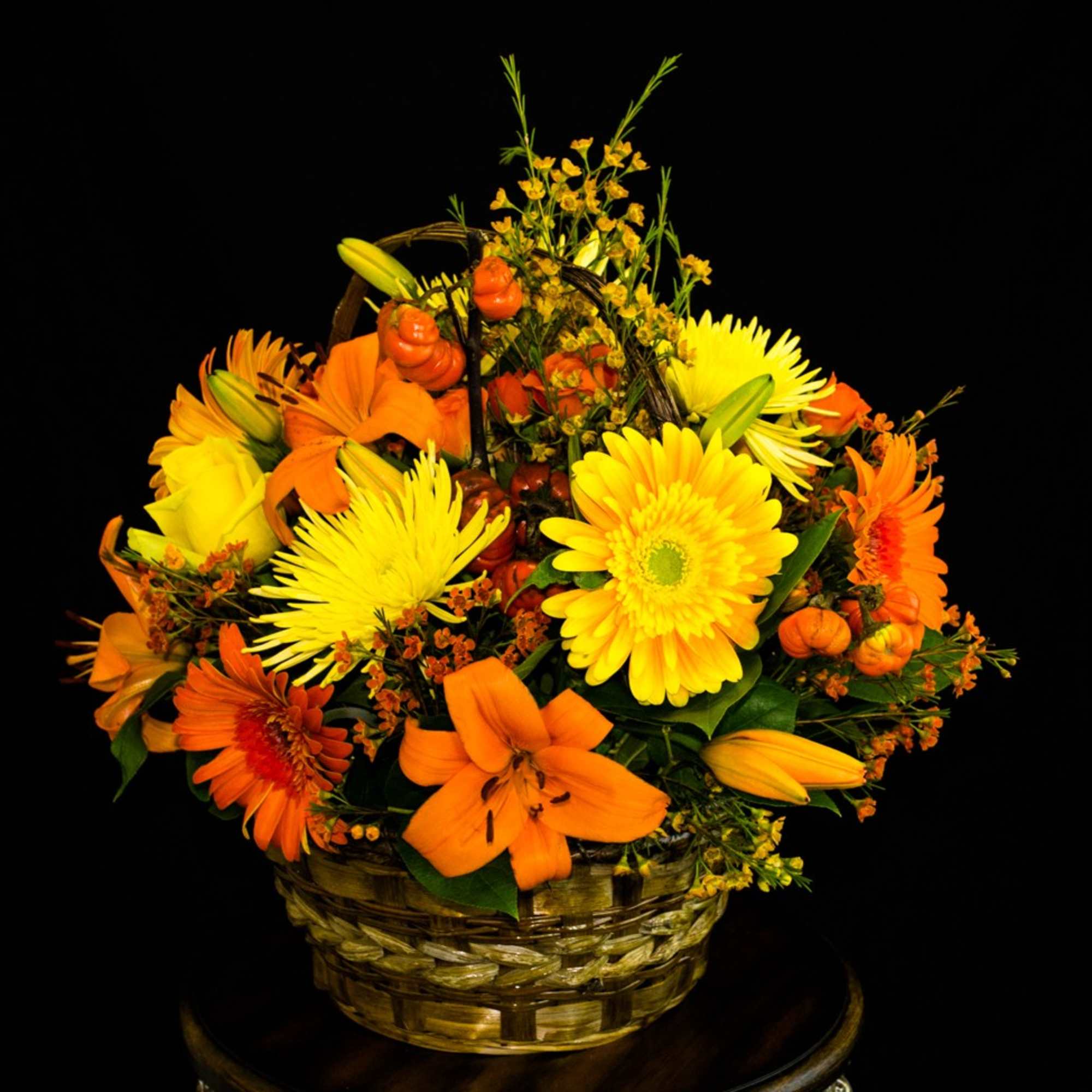 Basket arrangement of yellow and orange flowers with lilies and daisies
