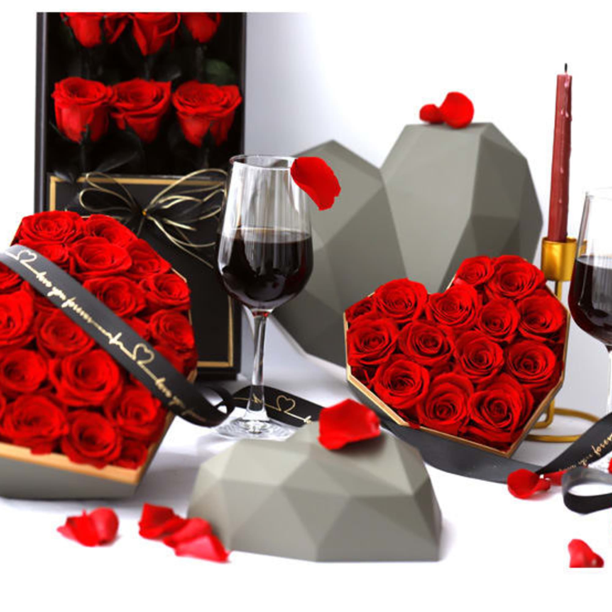 Heart-shaped boxes of red roses with wine glasses and candles