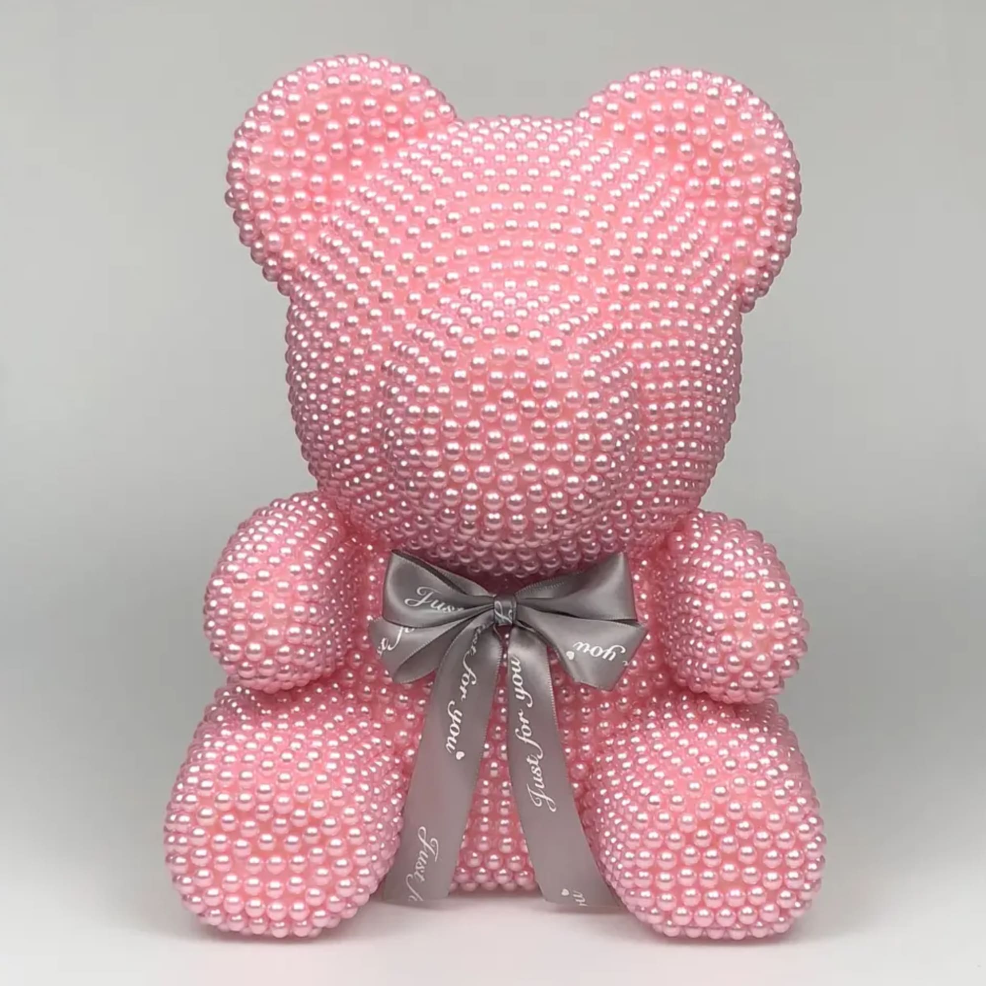 Pink beaded teddy bear with a gray ribbon bow