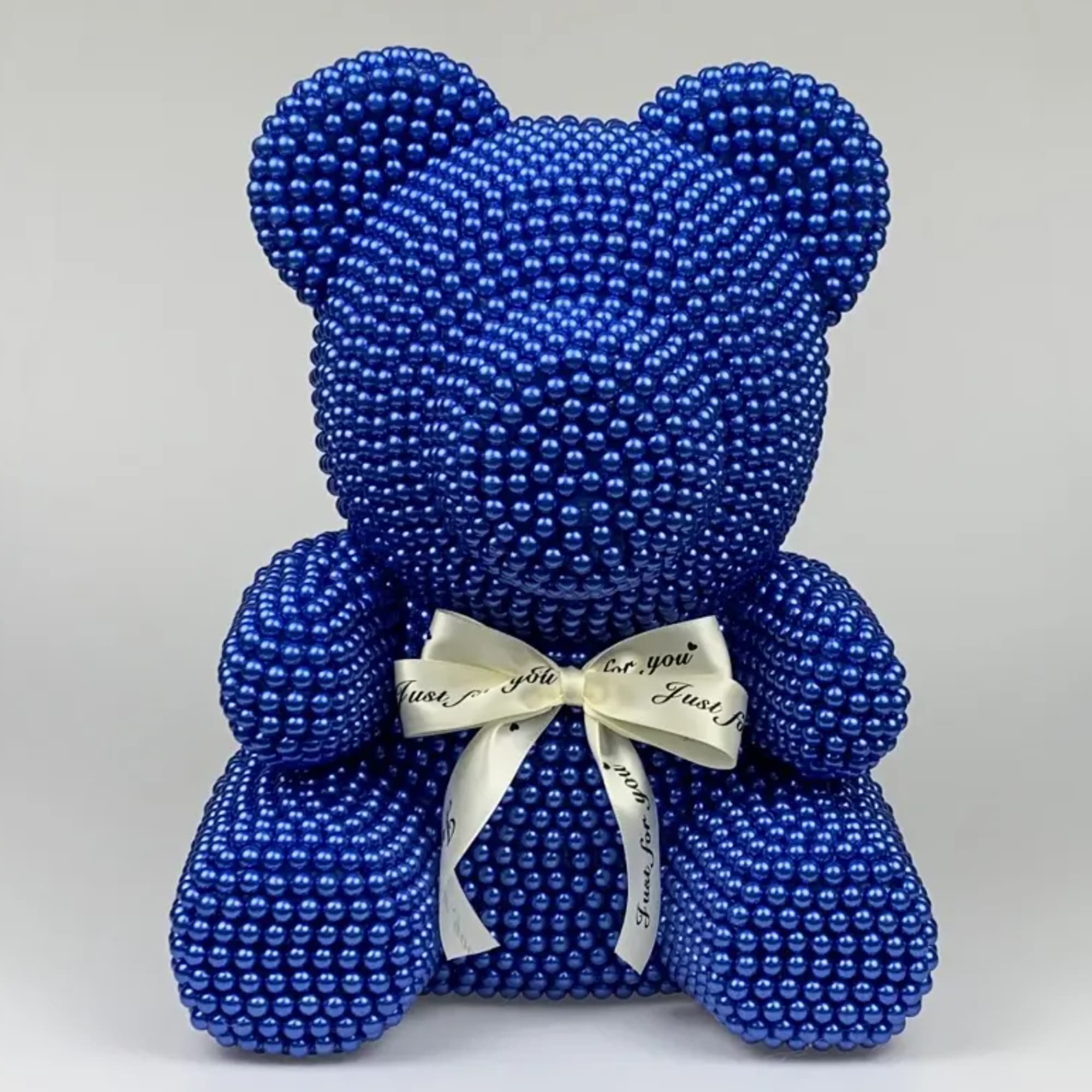 Blue beaded teddy bear with a white ribbon bow