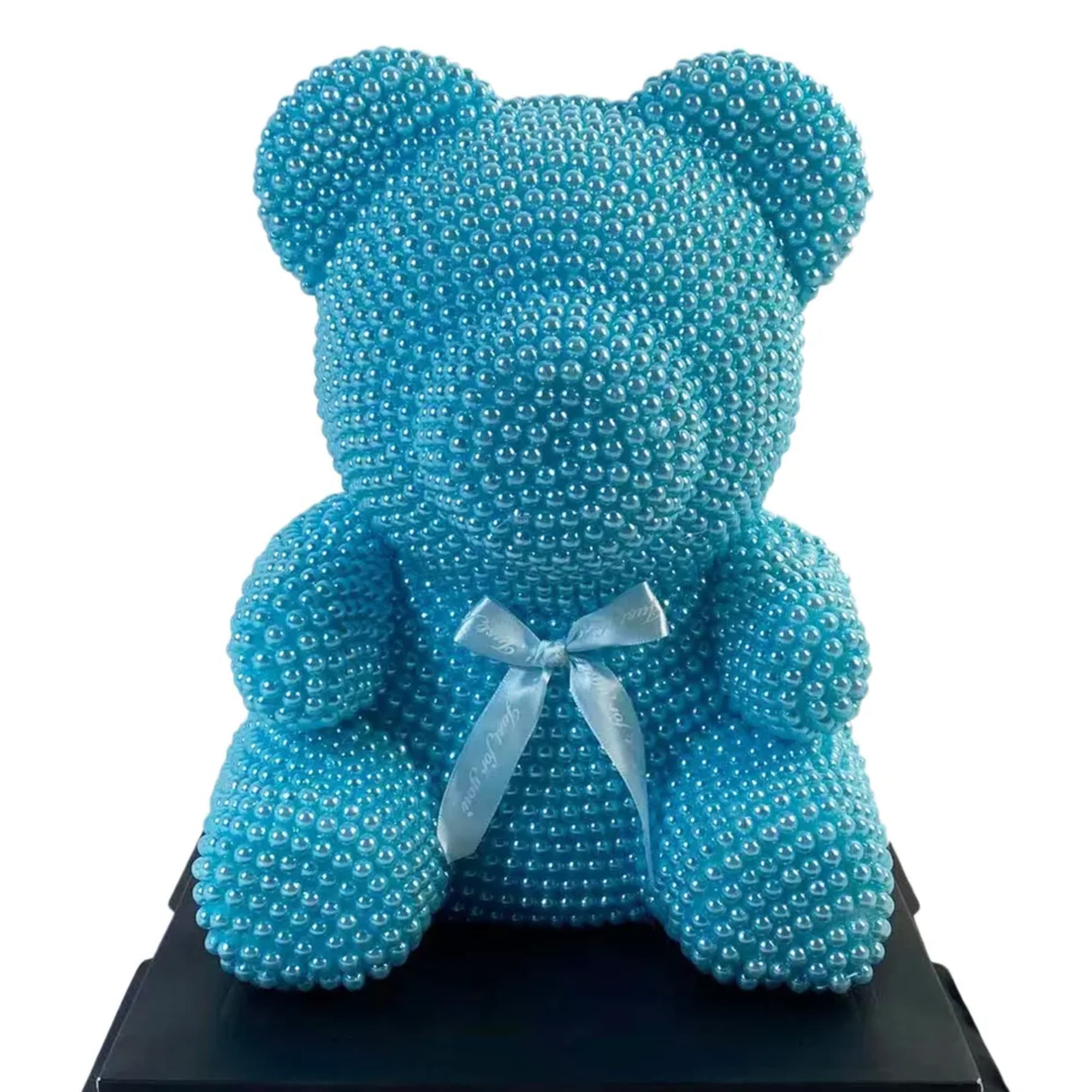 Blue teddy bear covered in beads with a ribbon bow