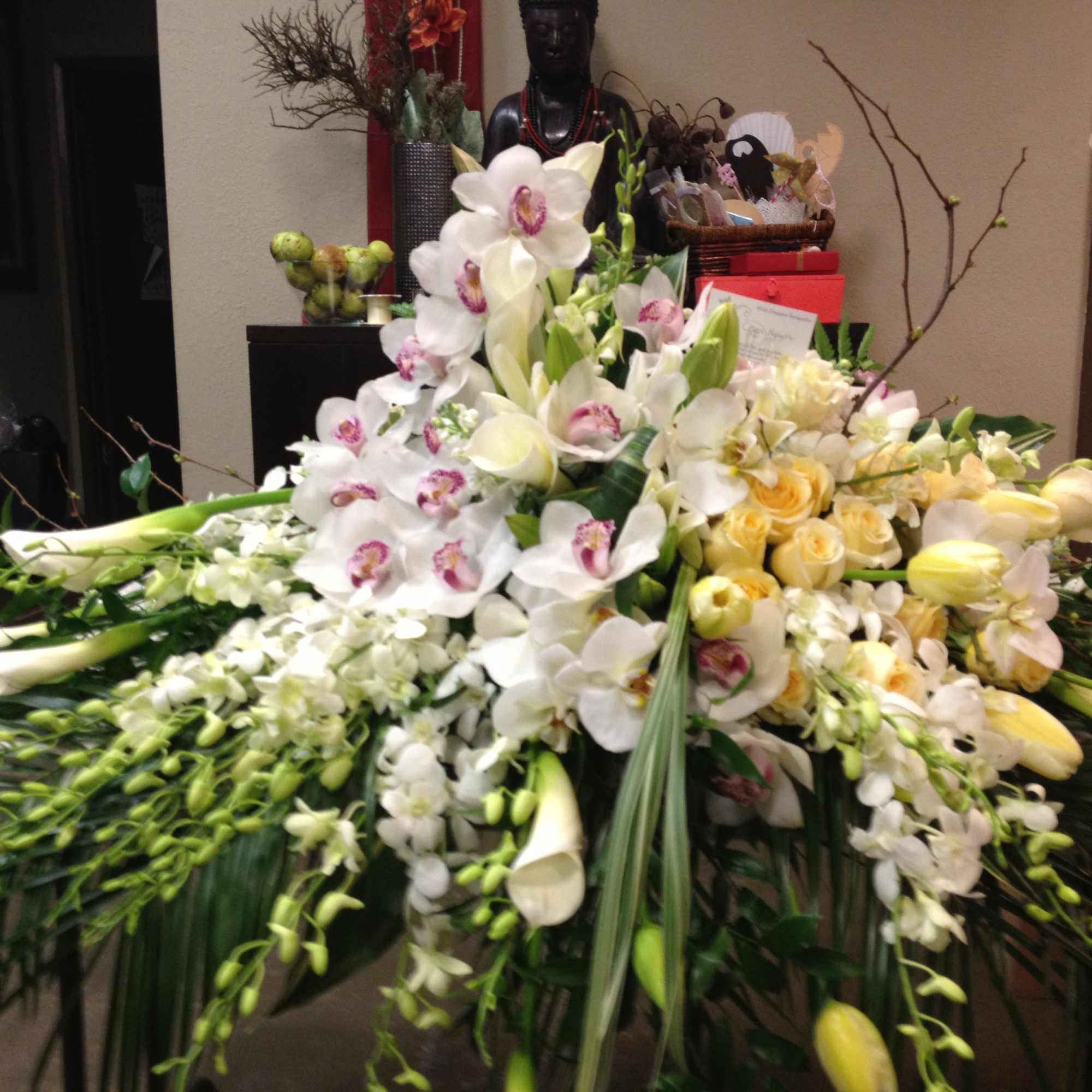Large white floral arrangement with orchids, roses, and calla lilies