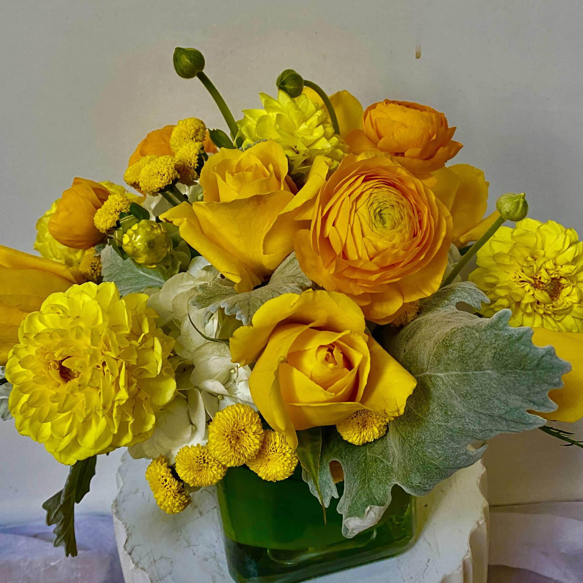 Yellow and orange bouquet in a green glass vase
