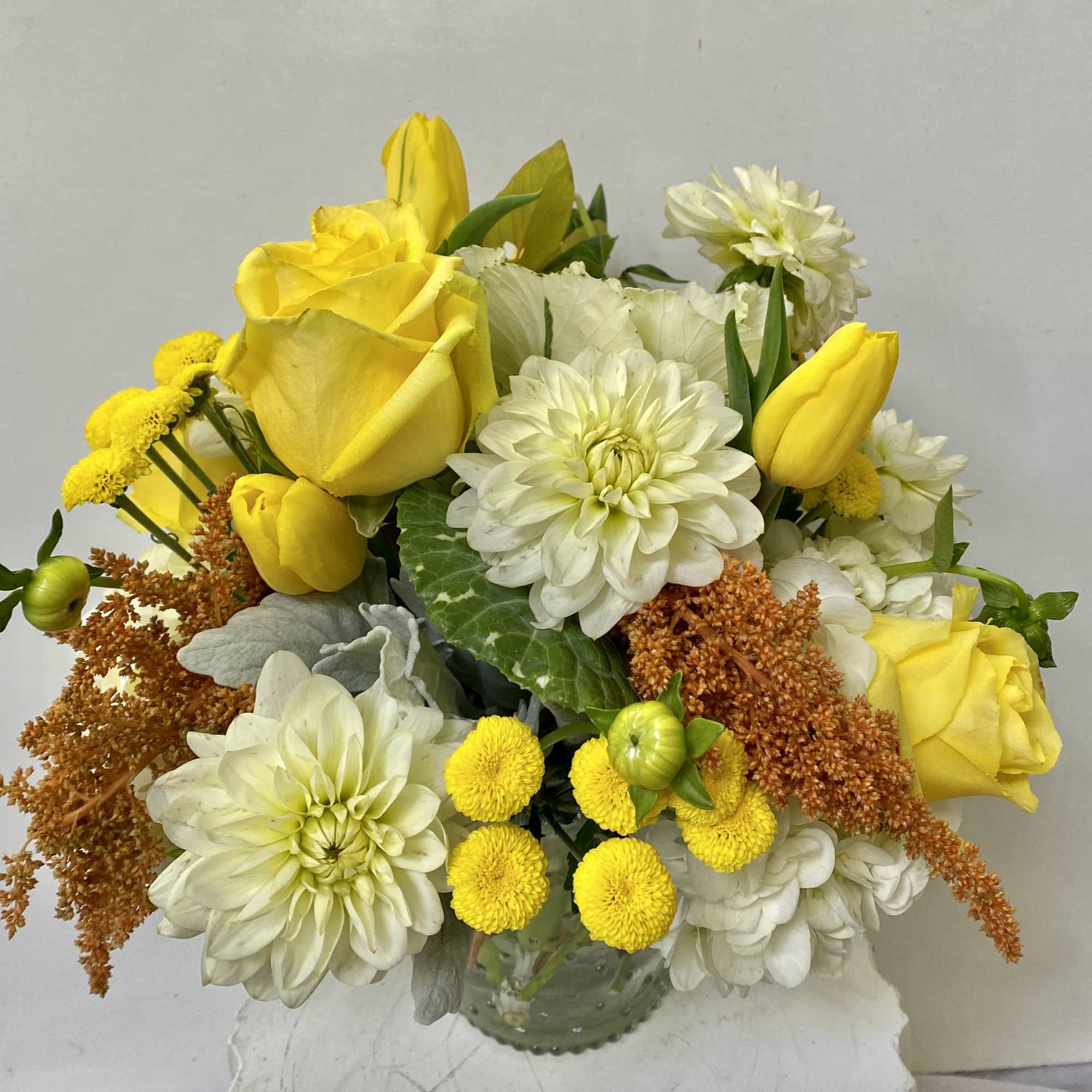 Yellow roses and white dahlias in a glass vase