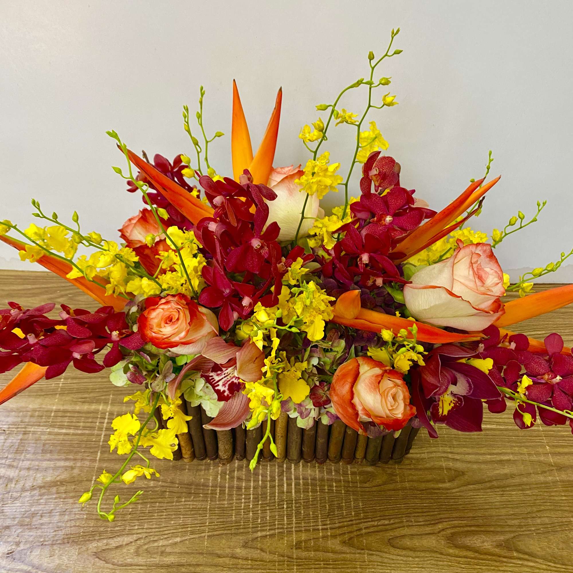 Tropical bouquet with orange birds of paradise, red orchids, and peach roses