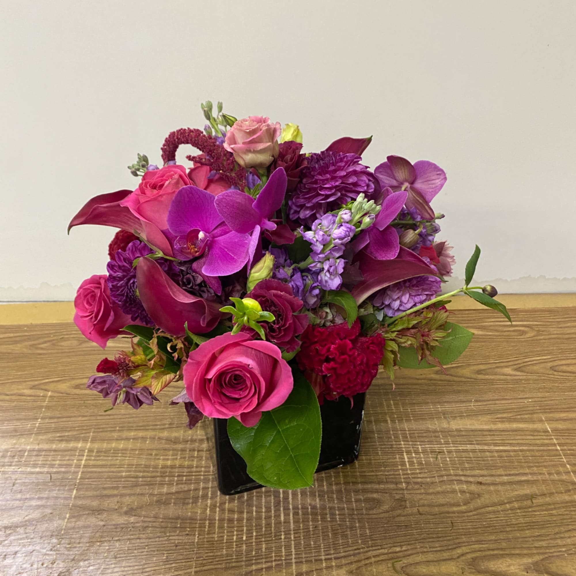 Pink and purple floral arrangement in a black square vase