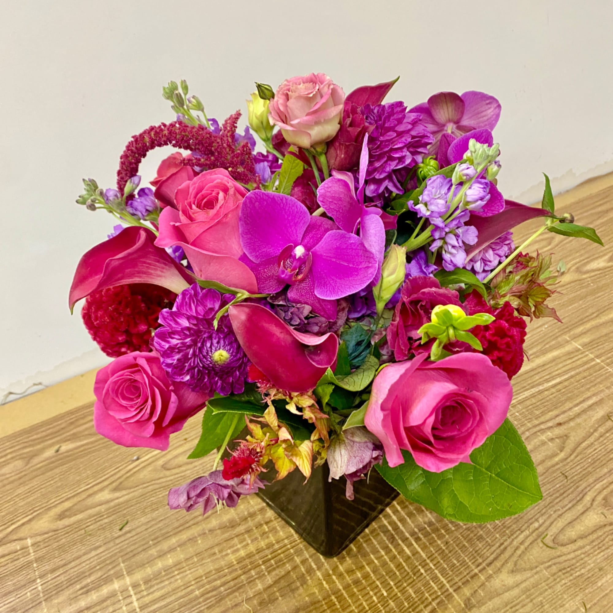Pink and purple mixed flower arrangement in a black square vase