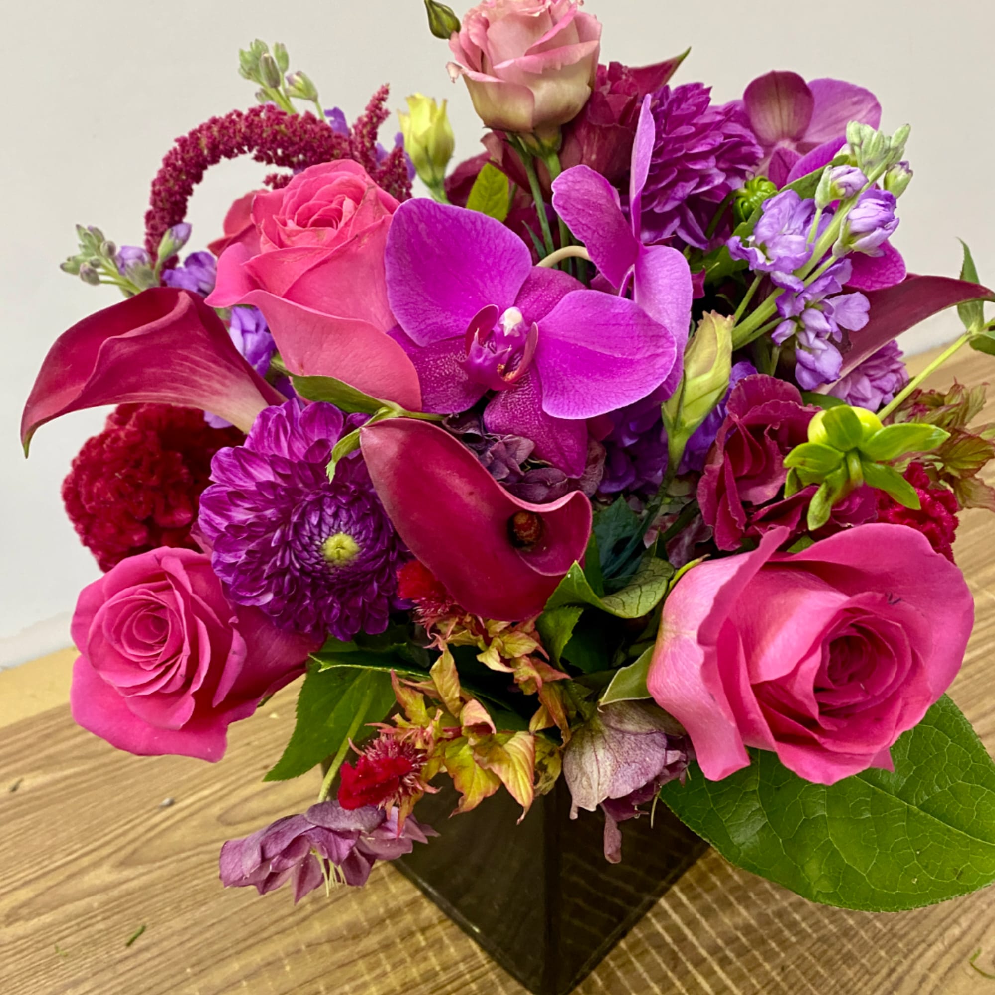 Pink roses and purple orchids in a black vase
