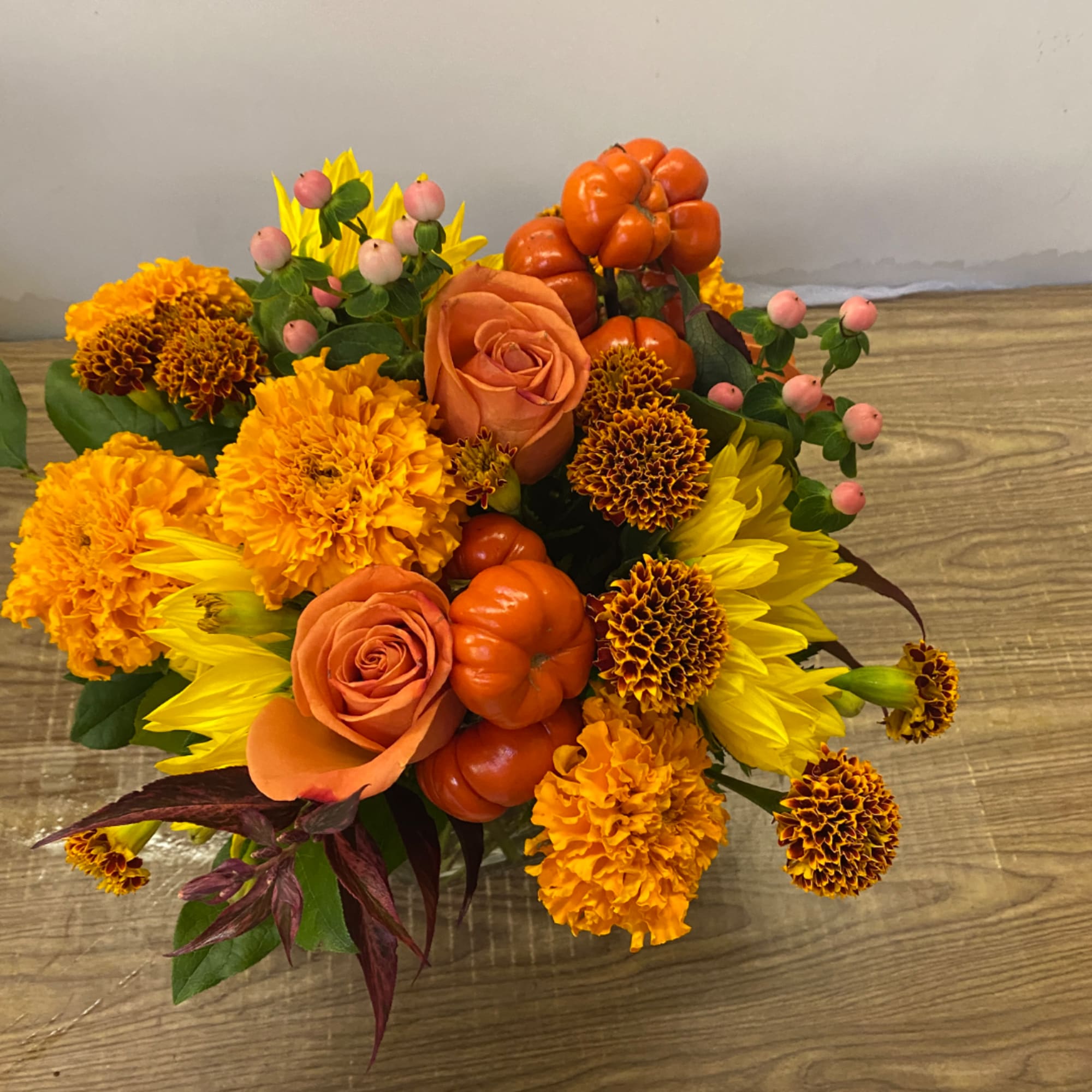 Orange and yellow bouquet with roses, marigolds, and sunflowers