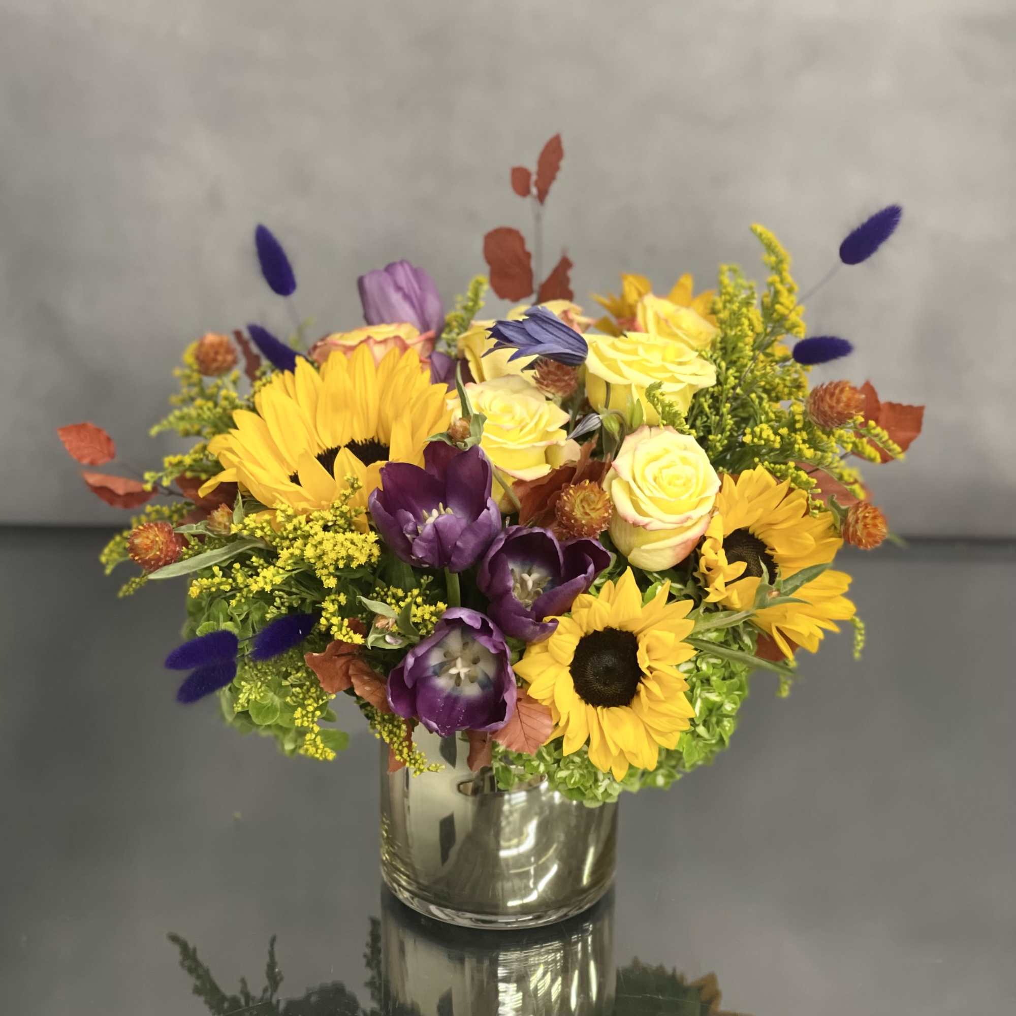 Deliver happiness with this abundant fall floral including sunflower, tulips, roses and