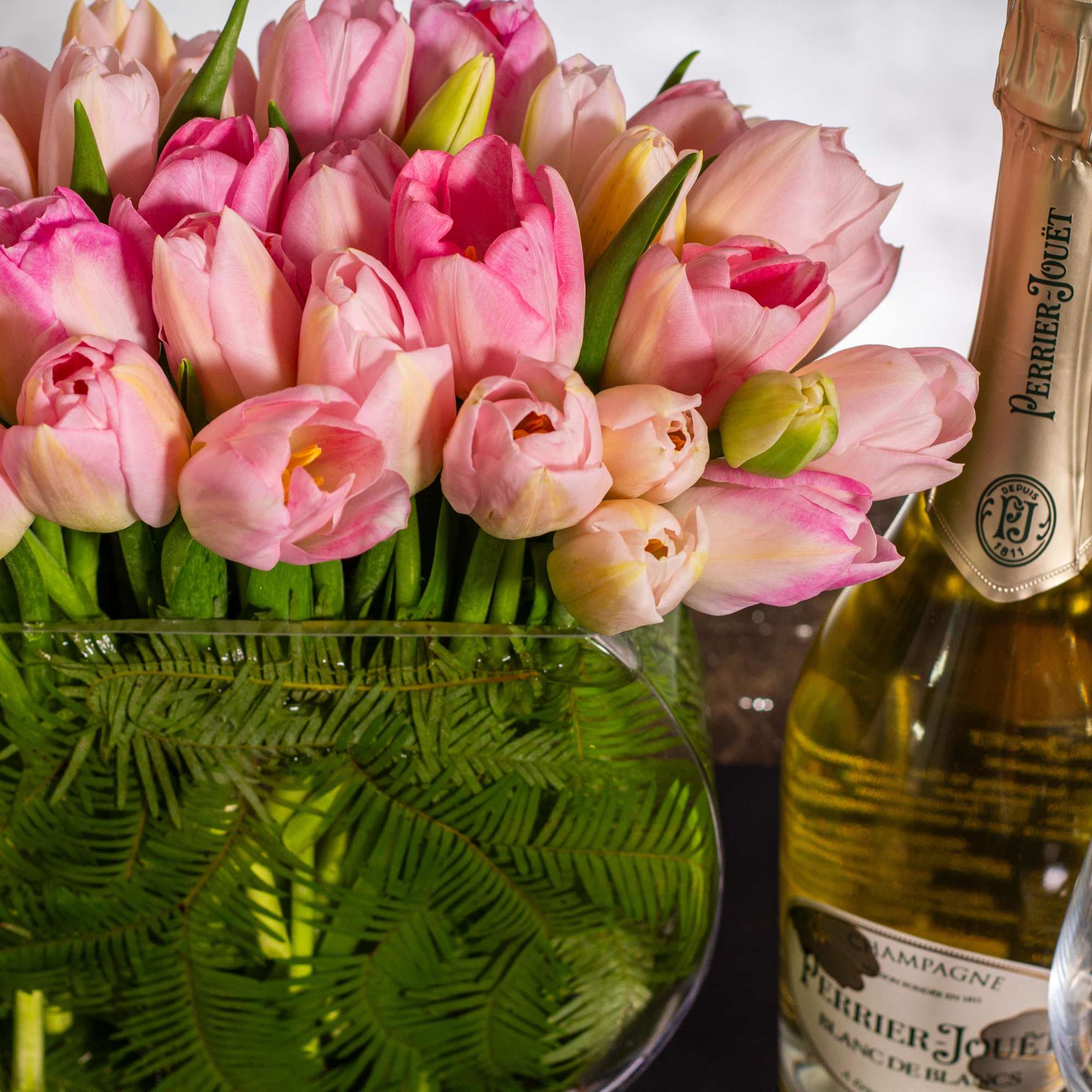 The beautiful arrangement showcases 50 tulips gathered in a modern vase, creating, photo 2 of 5
