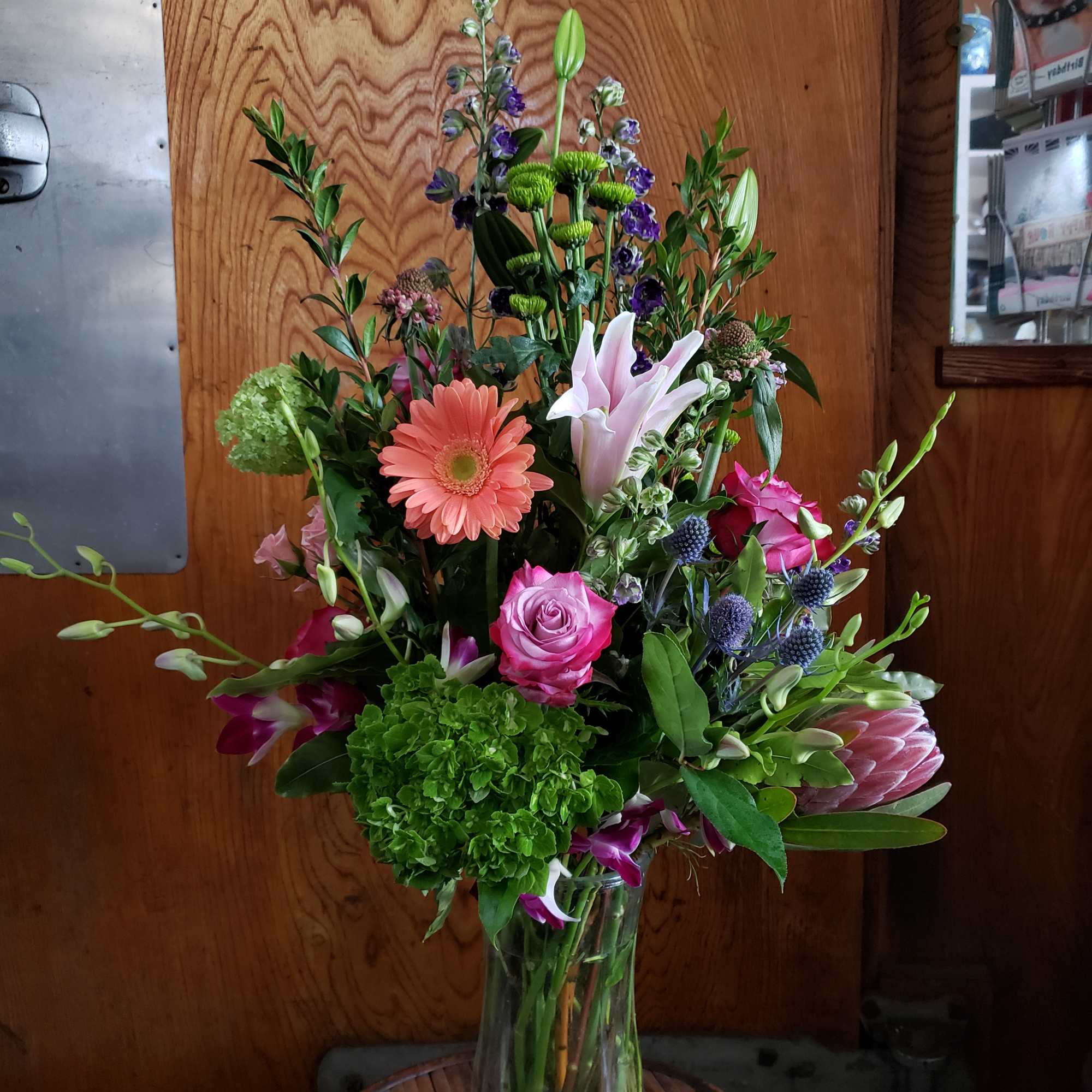 Tall mixed bouquet in a clear glass vase with pink, white, and green blooms