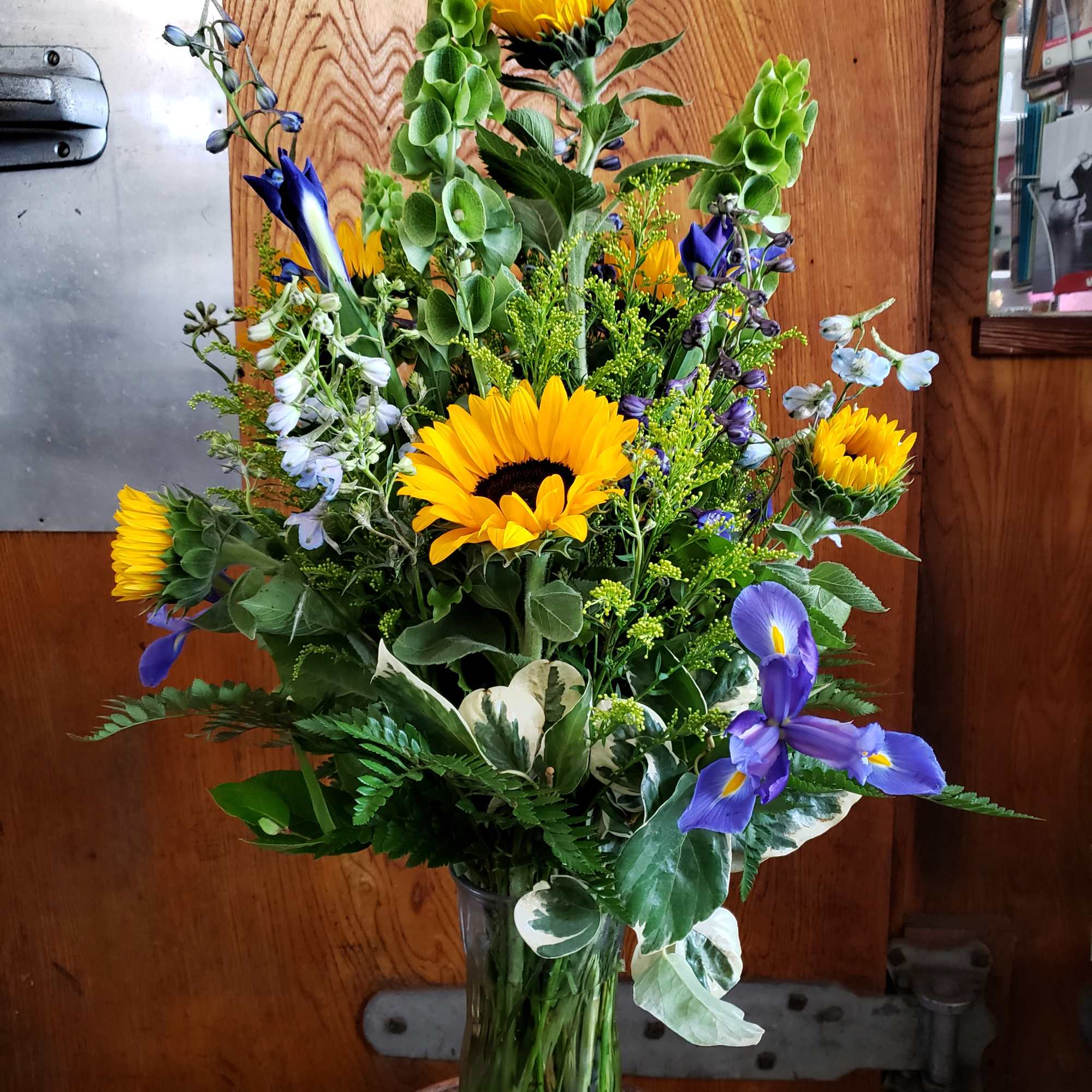 Tall mixed bouquet with sunflowers and purple iris in a glass vase