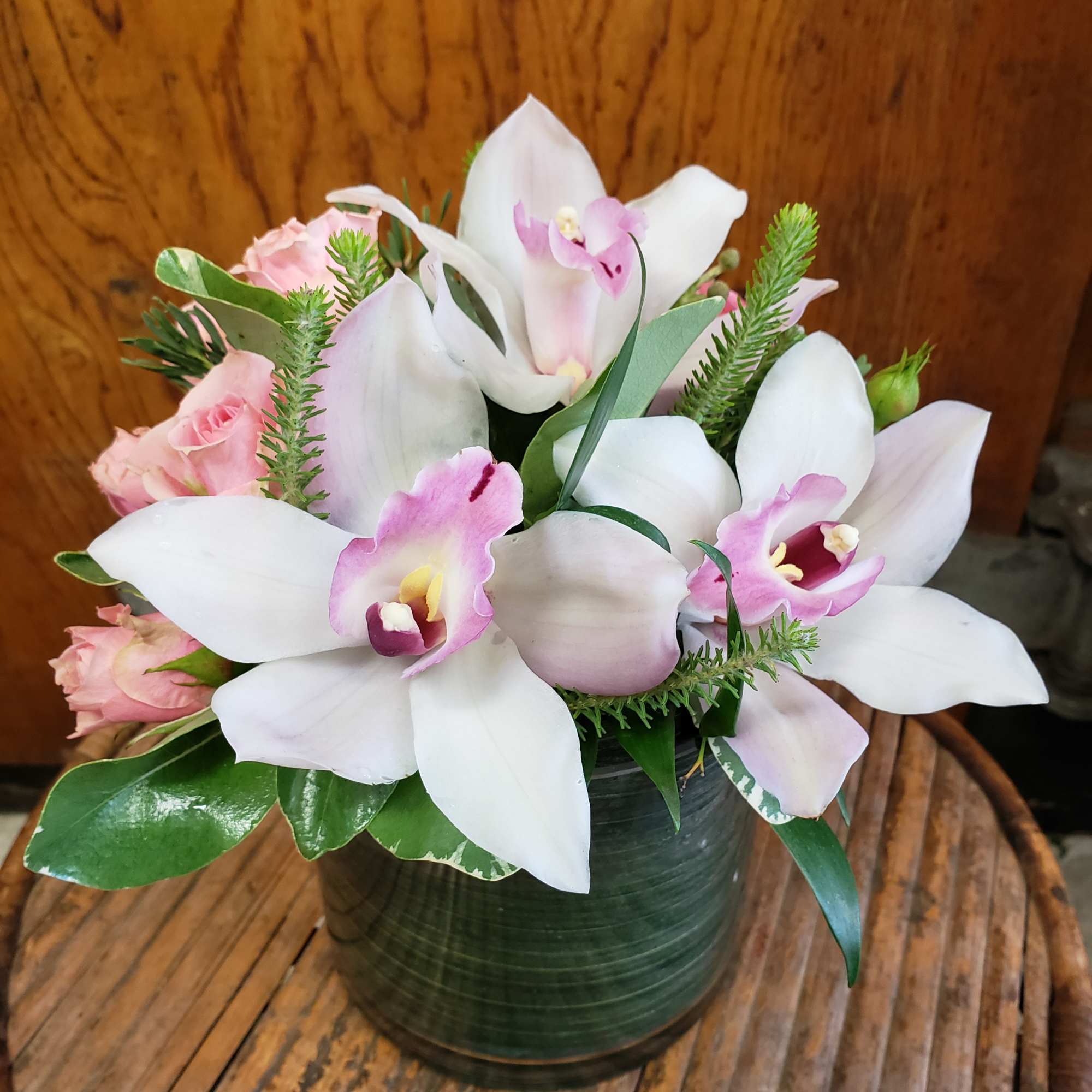 Elegant cymbidum orchids are showcased in a cylinder vase, accompanied by spray