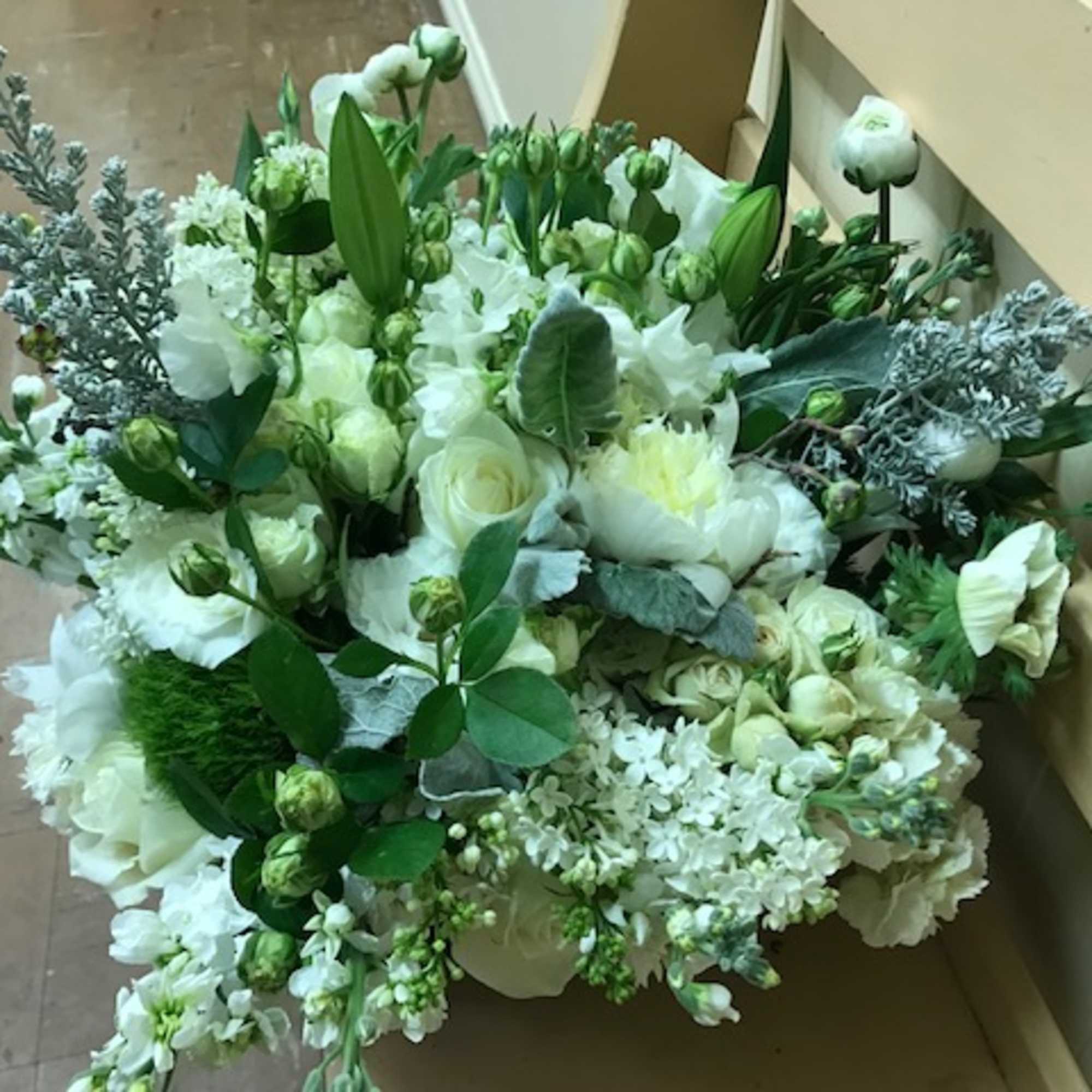 Large white floral arrangement with mixed blooms and greenery