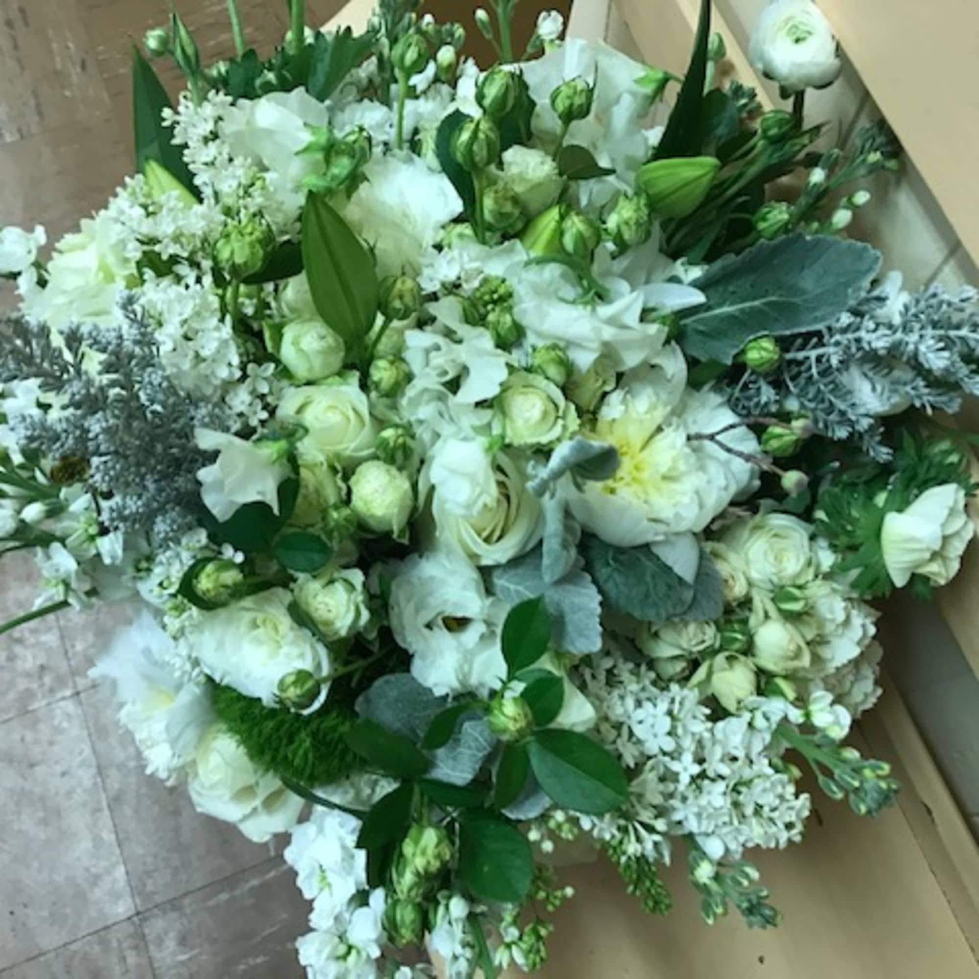 White floral arrangement with roses and lilies in a low cluster