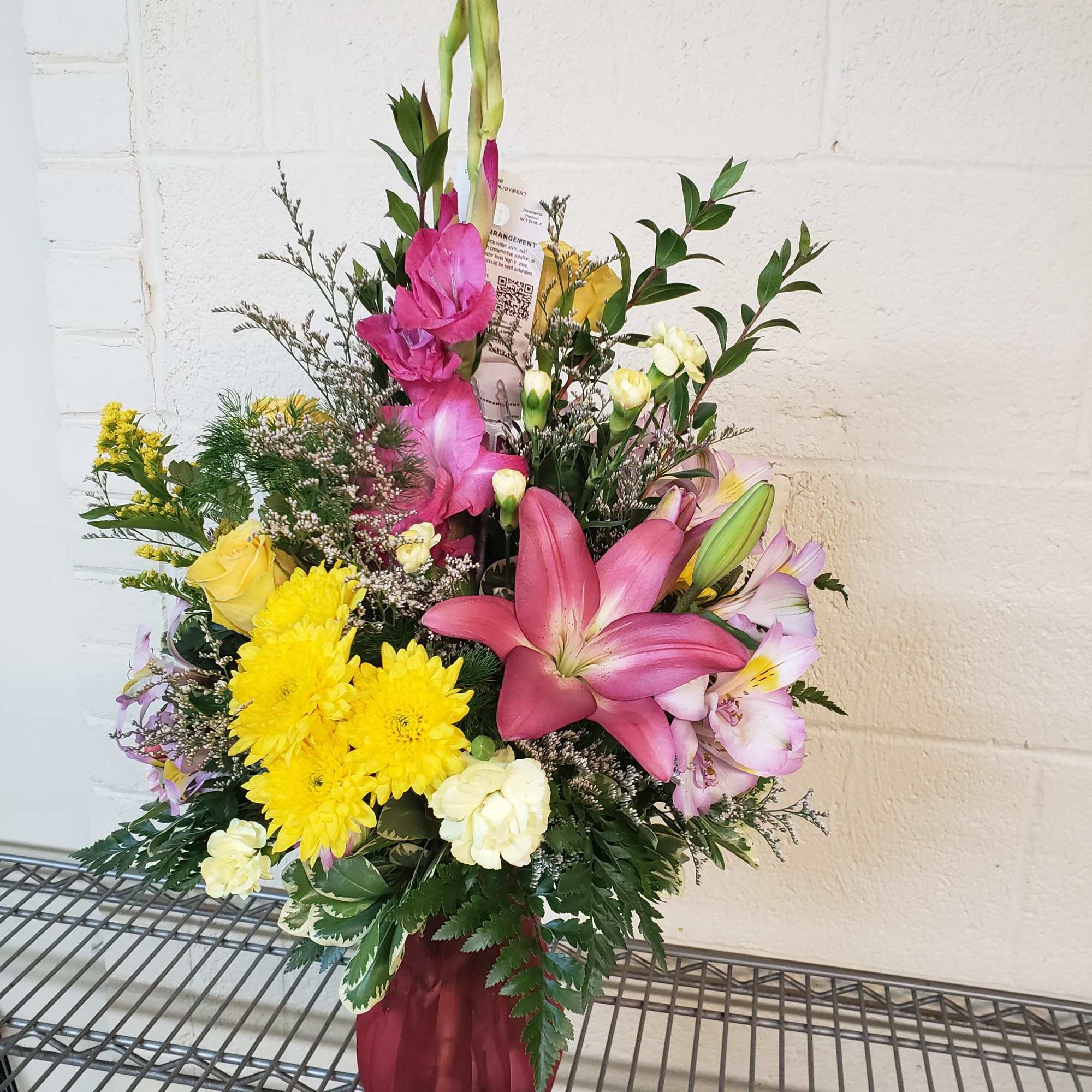 Mixed bouquet with pink lilies, yellow chrysanthemums, and roses in a burgundy vase
