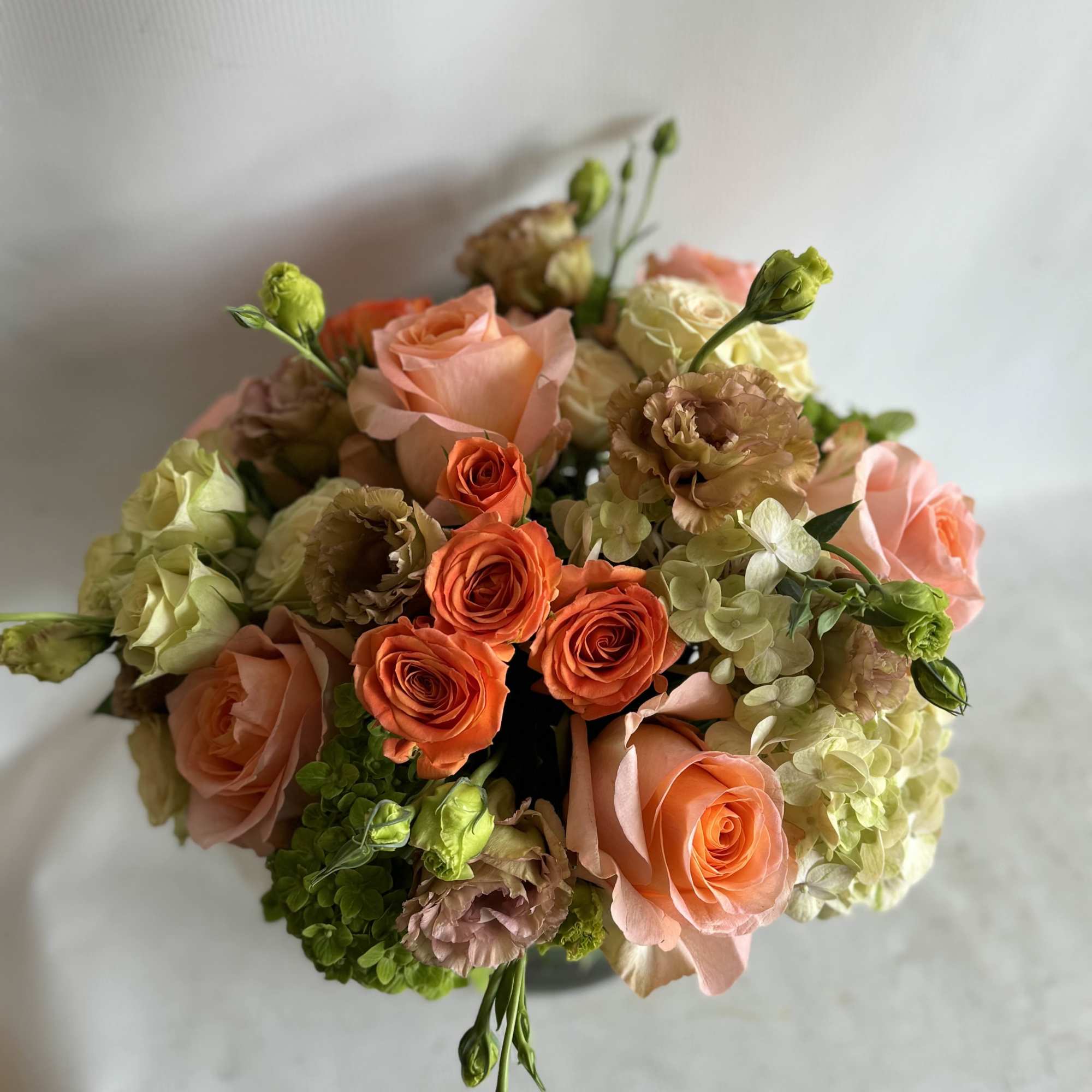 Bouquet of peach and orange roses with pale hydrangeas