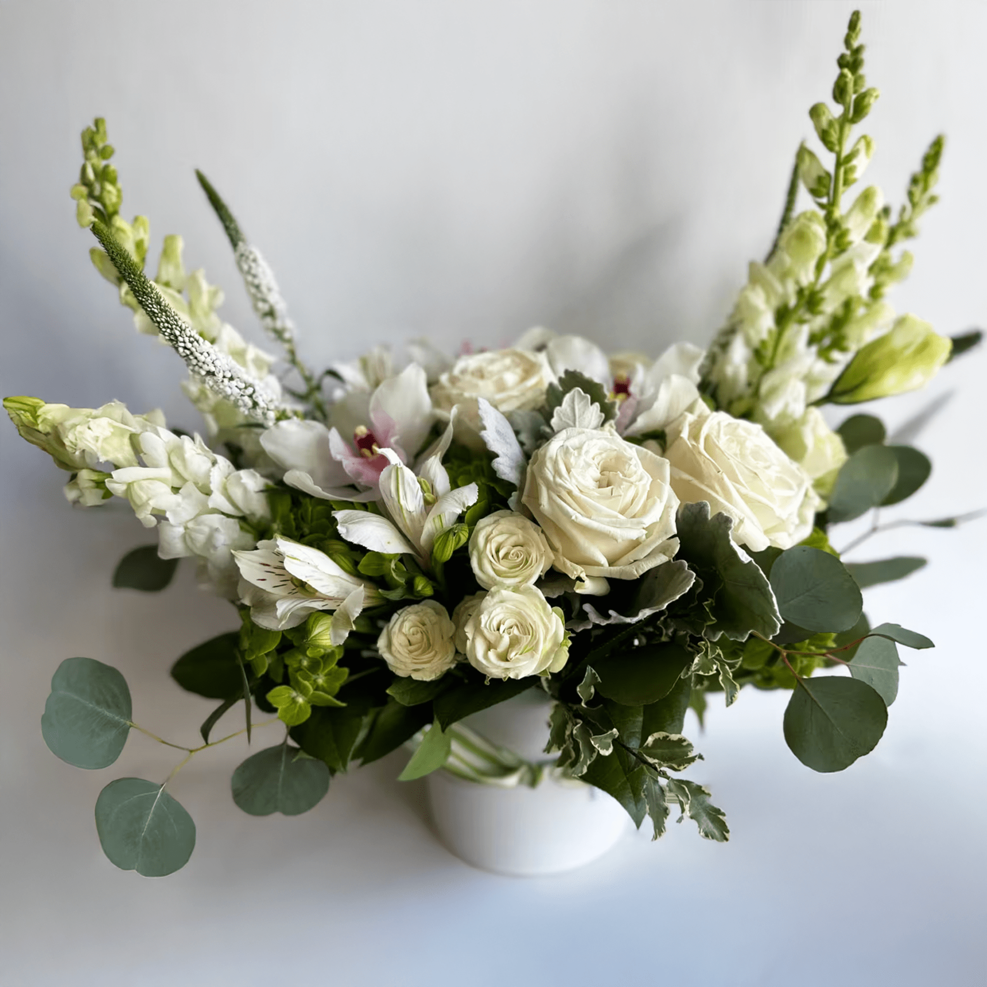 White rose bouquet with snapdragons in a white vase