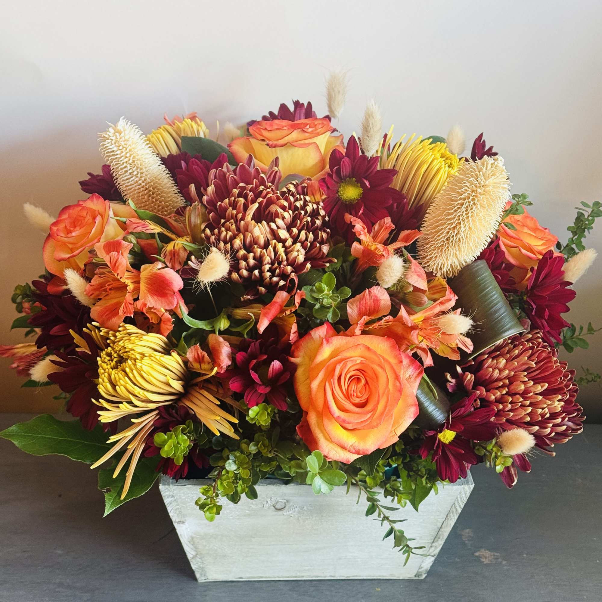 A fall inspired arrangement with lilies, sunflowers, roses, stem roses, hypericum berries