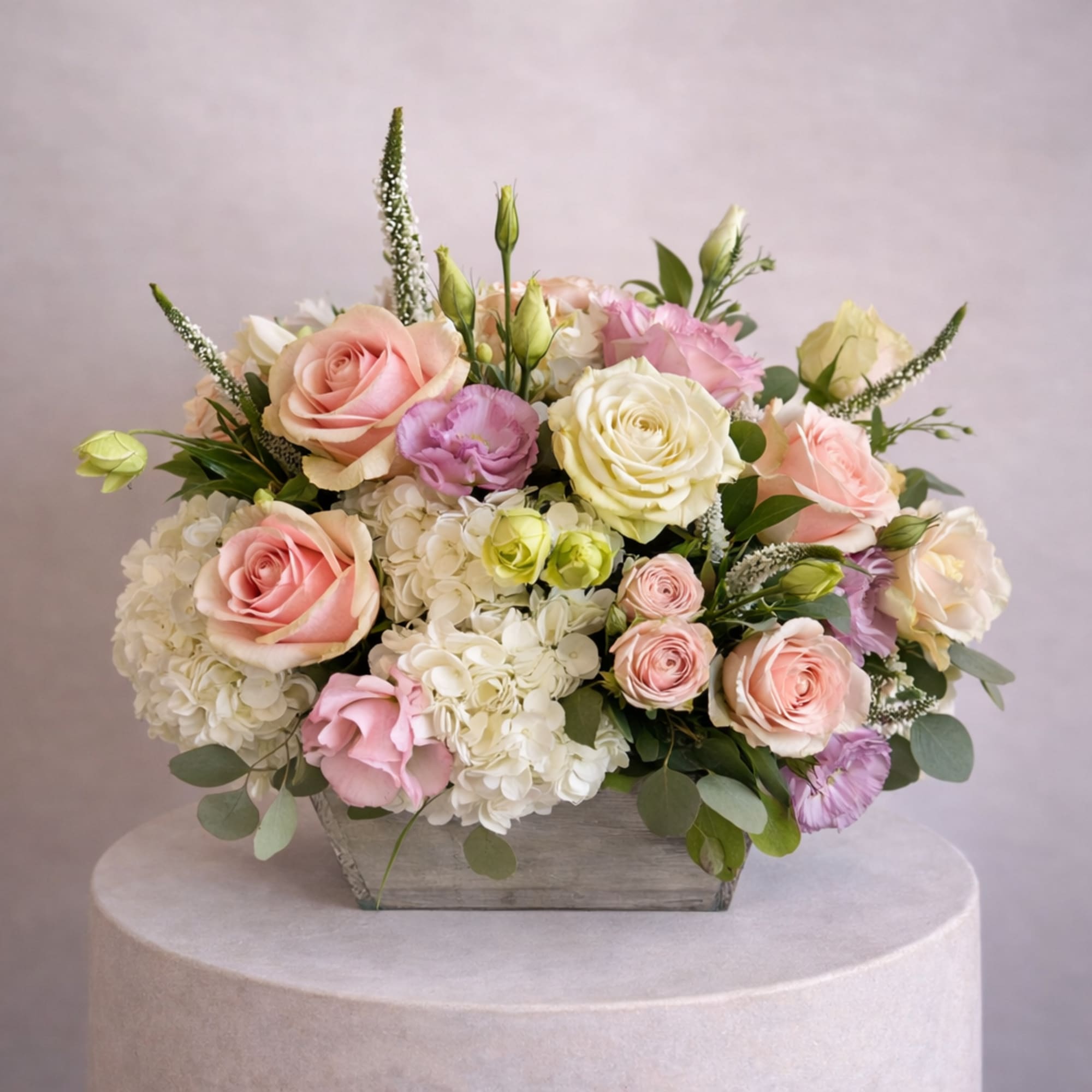 Low arrangement of pastel pink and ivory roses with white hydrangeas in a rustic wooden box