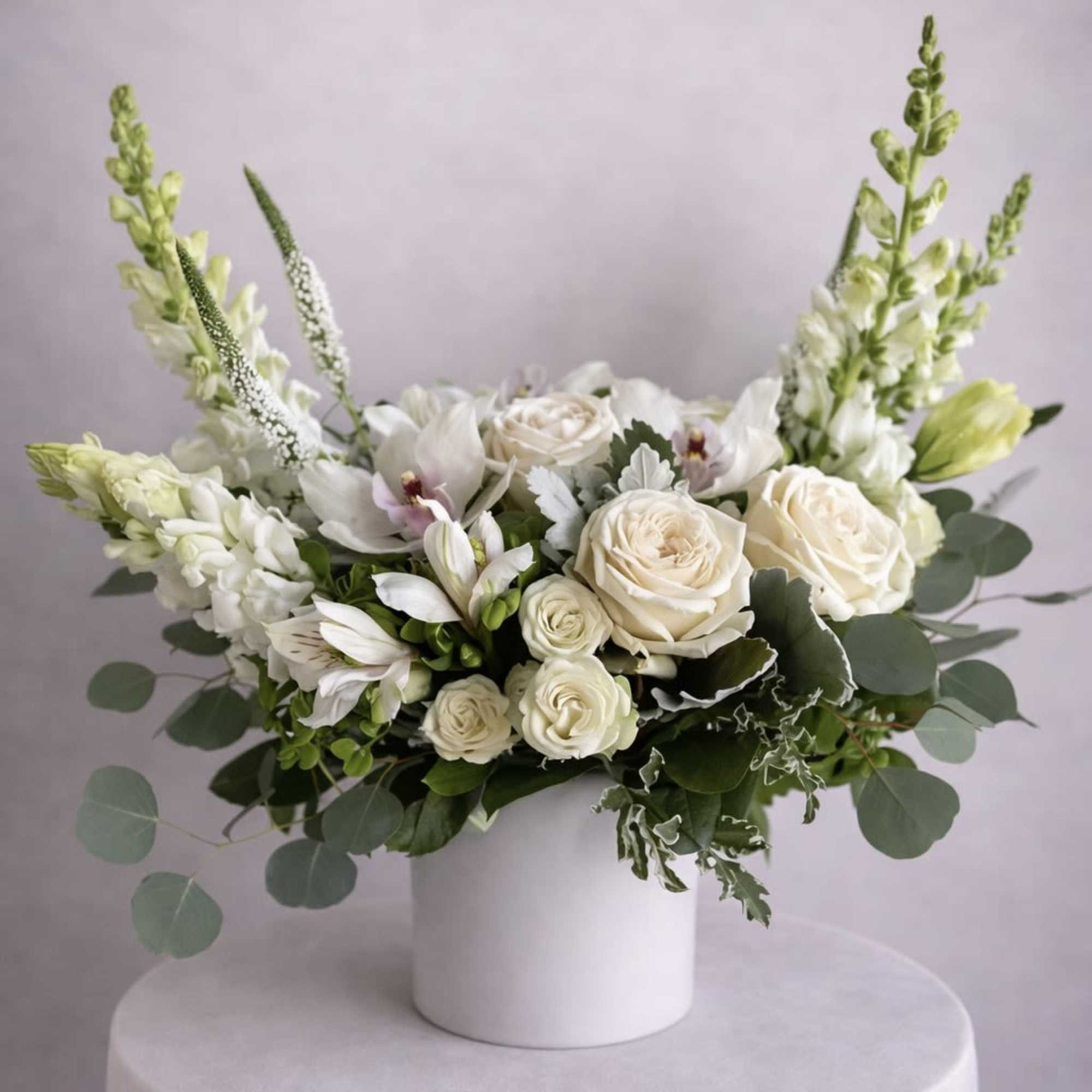 White rose and orchid arrangement in a white cylindrical vase