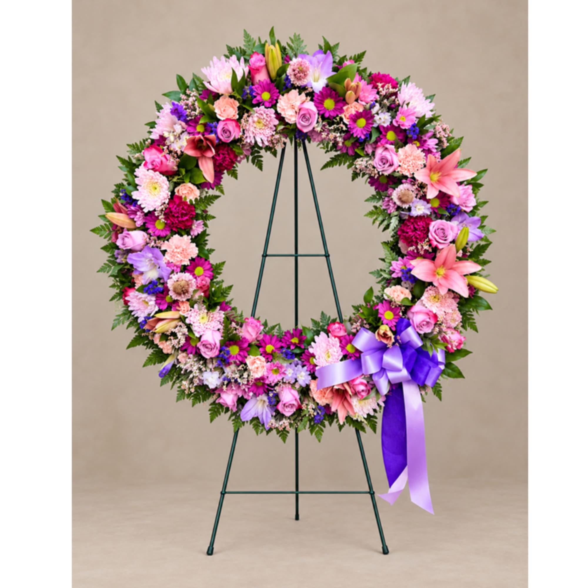 Circular floral wreath on an easel with a purple ribbon bow