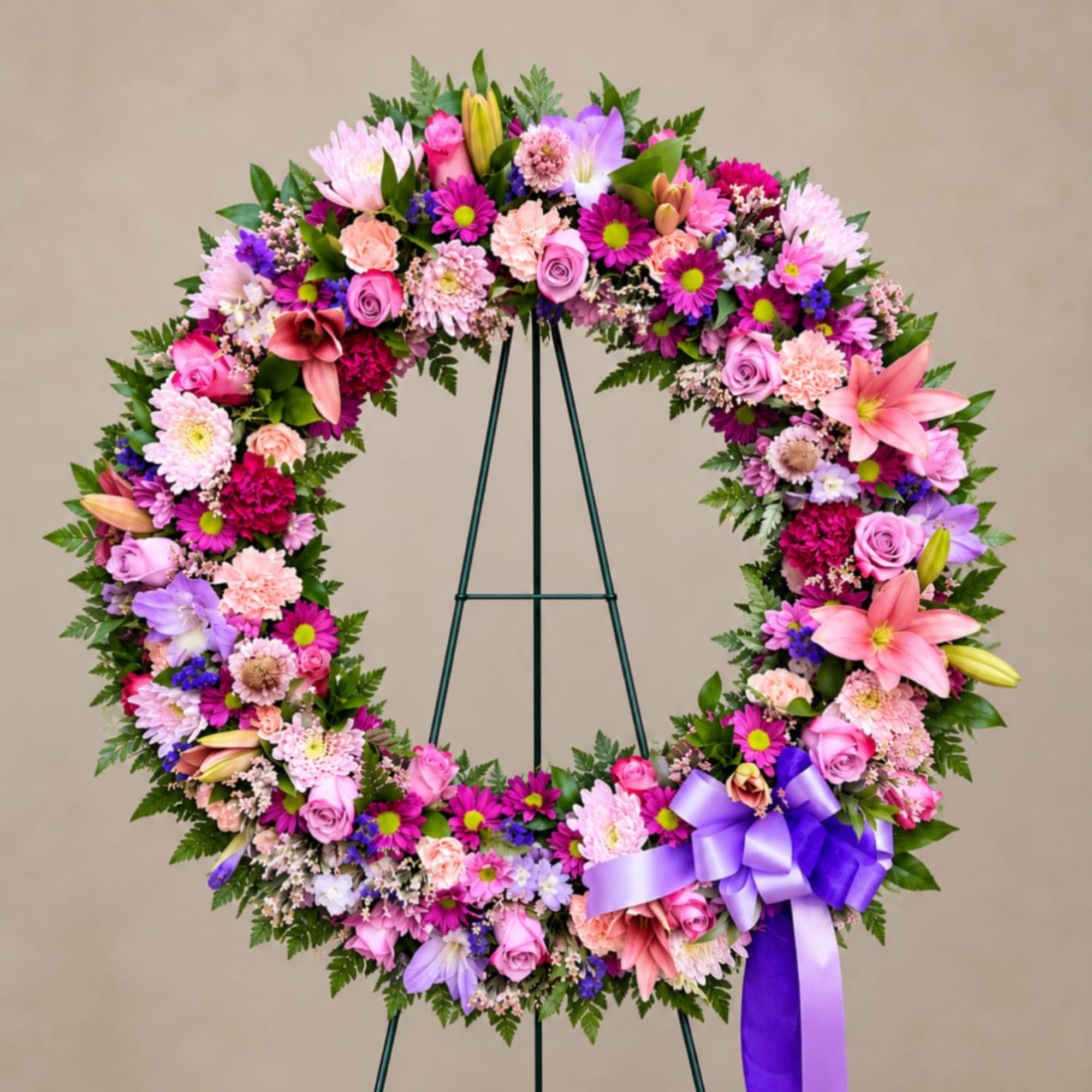 Large floral wreath with pink, purple, and white blooms on a stand