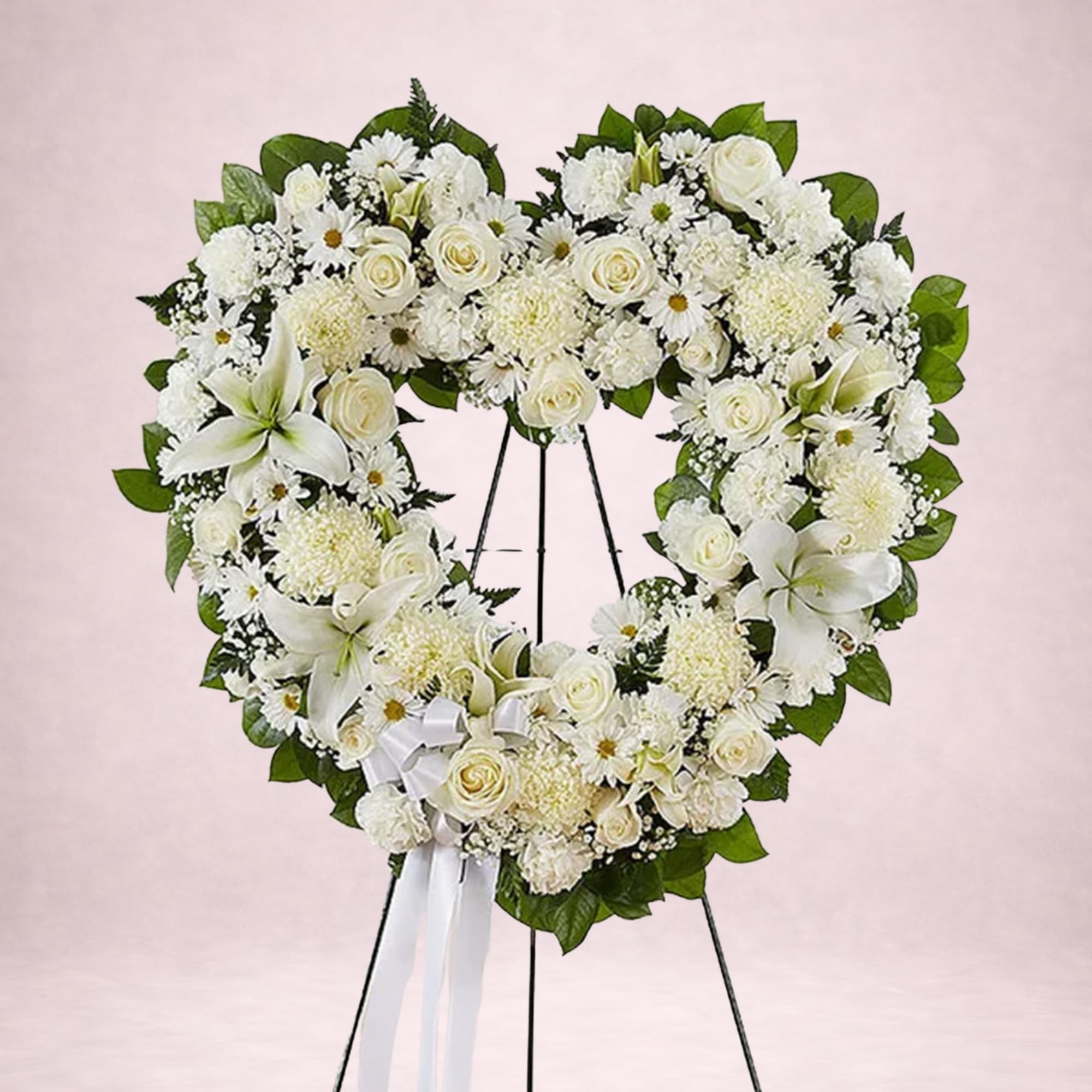 Heart-shaped white floral wreath on a stand with a ribbon bow