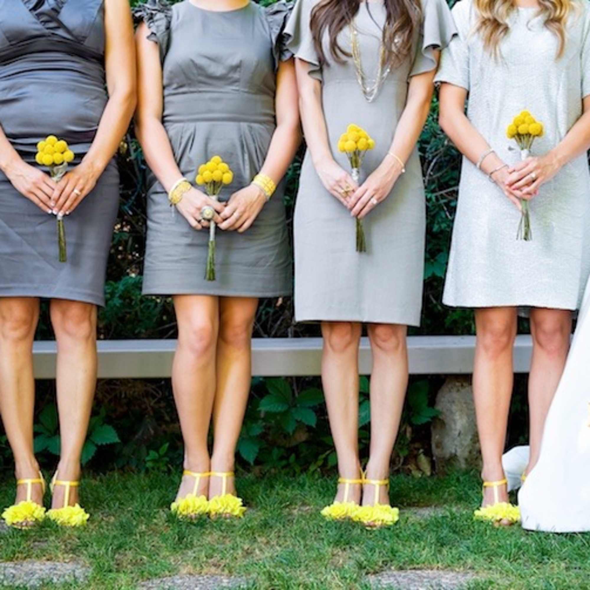 Bridesmaids and bride holding small yellow bouquets outdoors