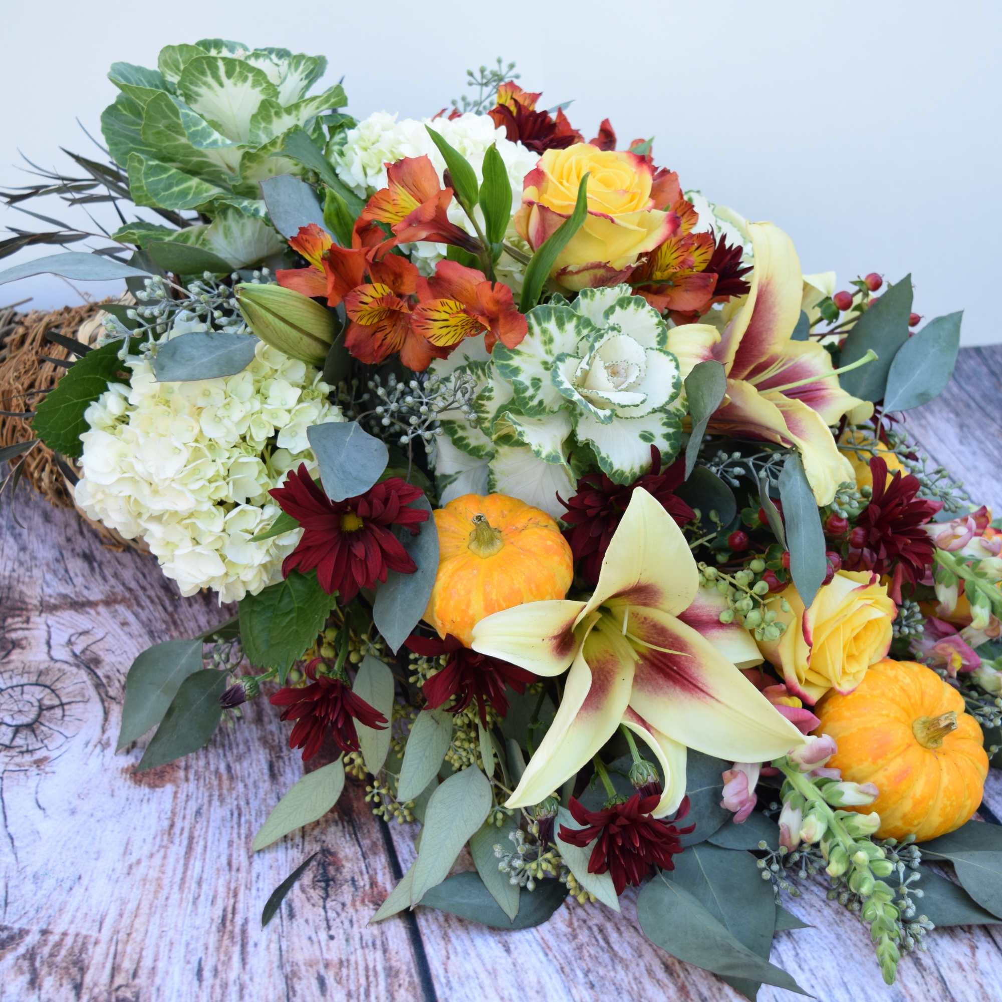 Autumn bouquet with lilies, roses, and small pumpkins