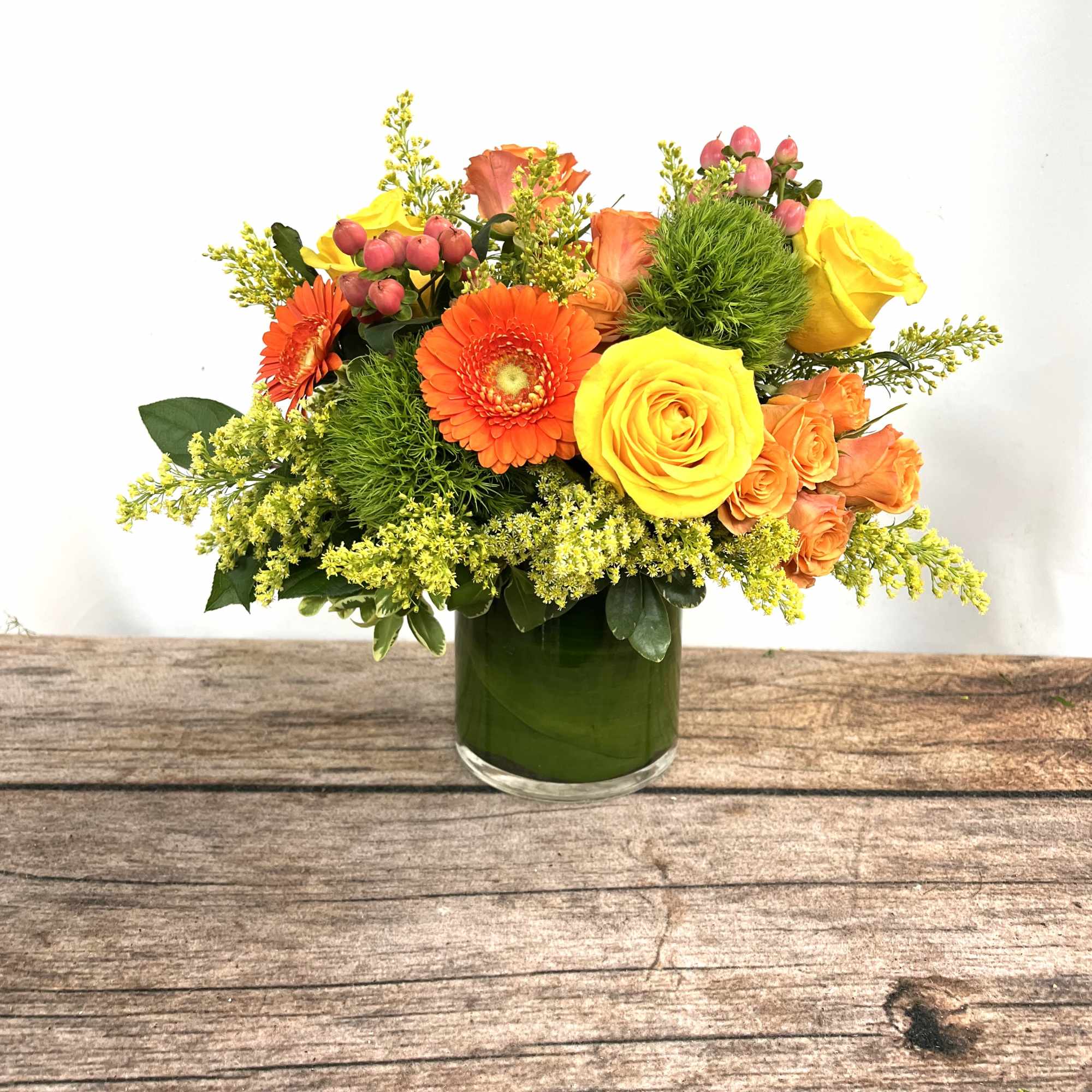 Orange and yellow flowers arranged in a green glass vase