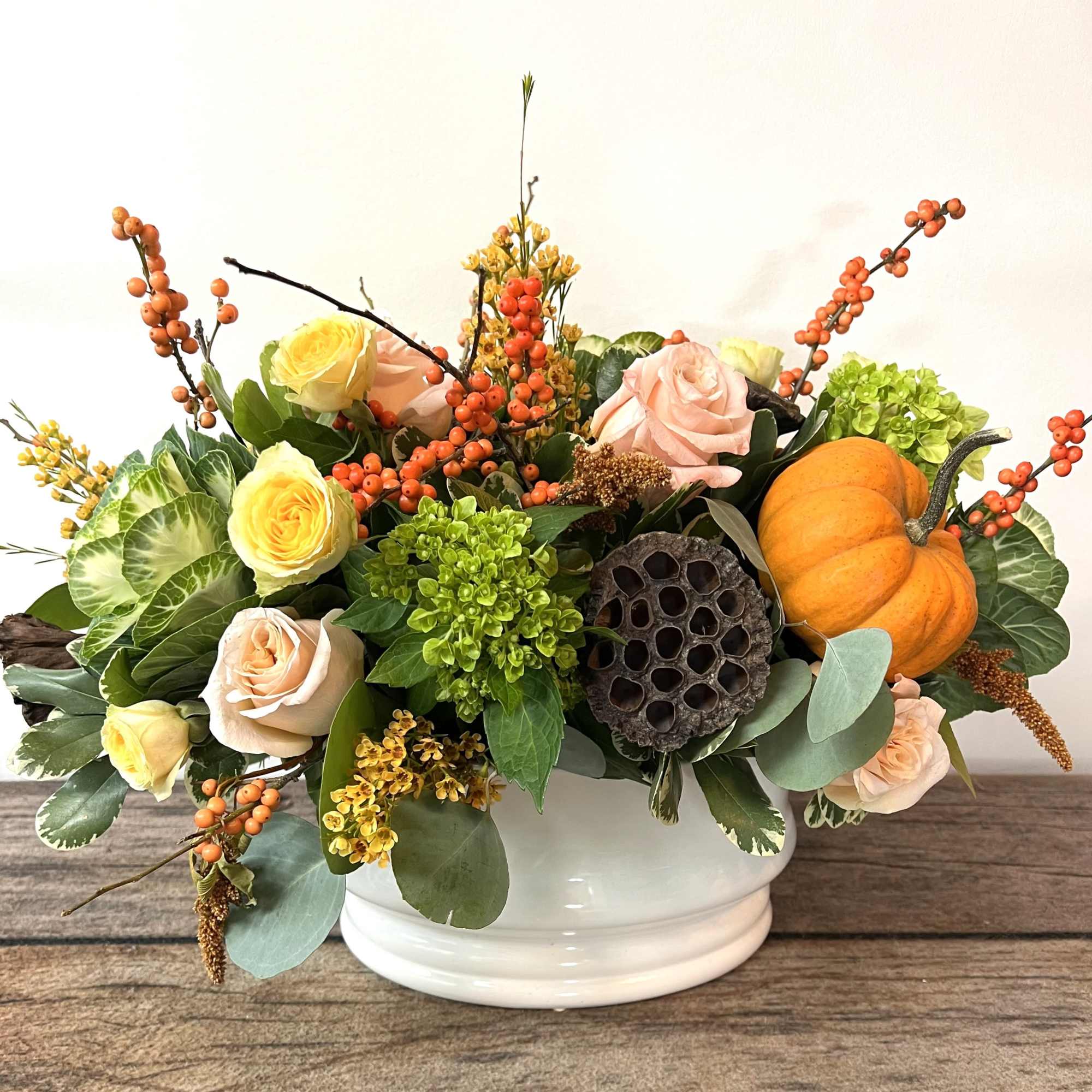 Mixed rose arrangement in a white bowl with a small pumpkin