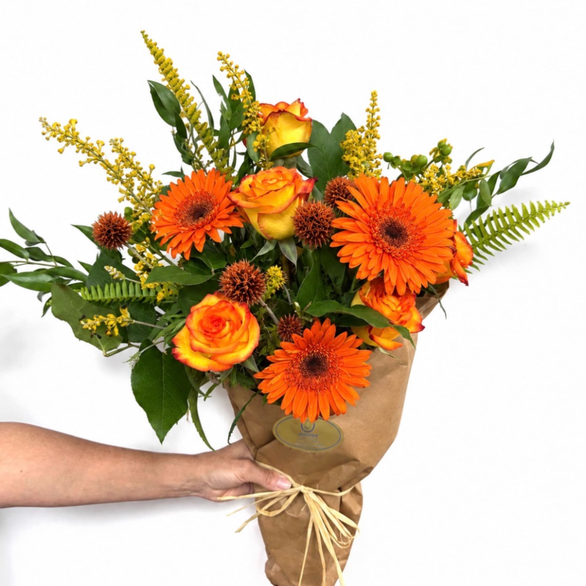 Orange gerbera daisies and roses in brown paper wrapping