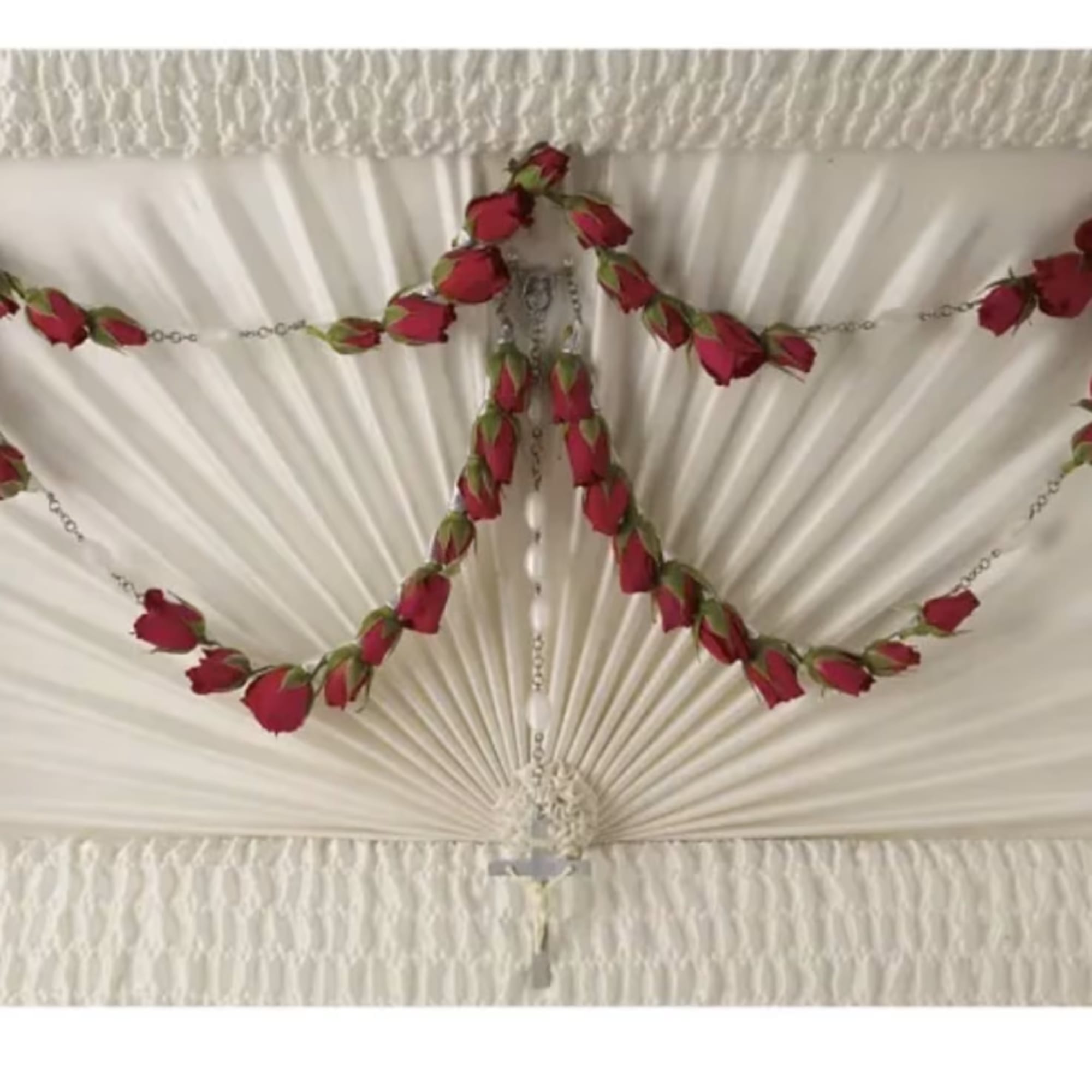 Red rose garland draped across a white pleated ceiling fan