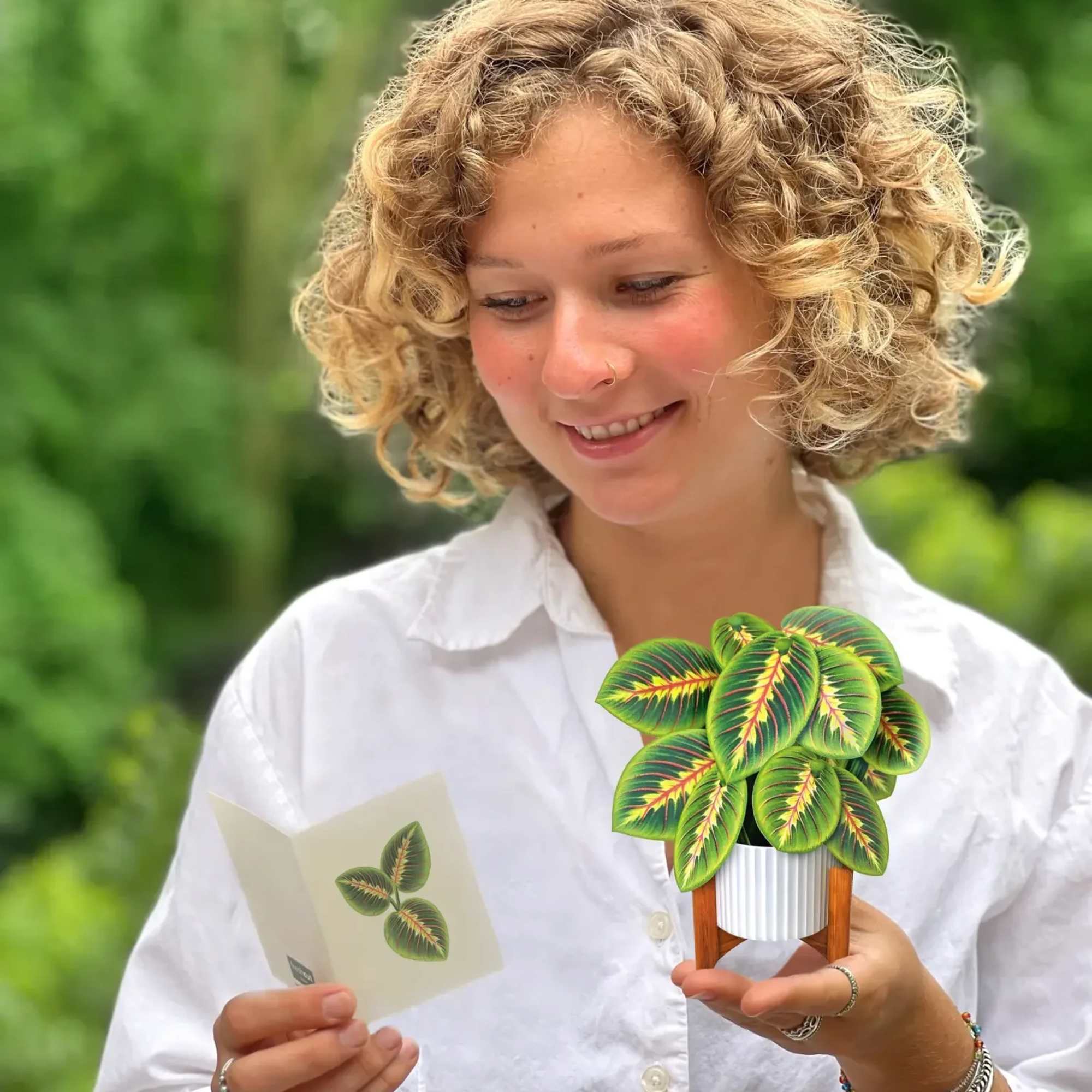 Woman holding a small potted plant and a matching card