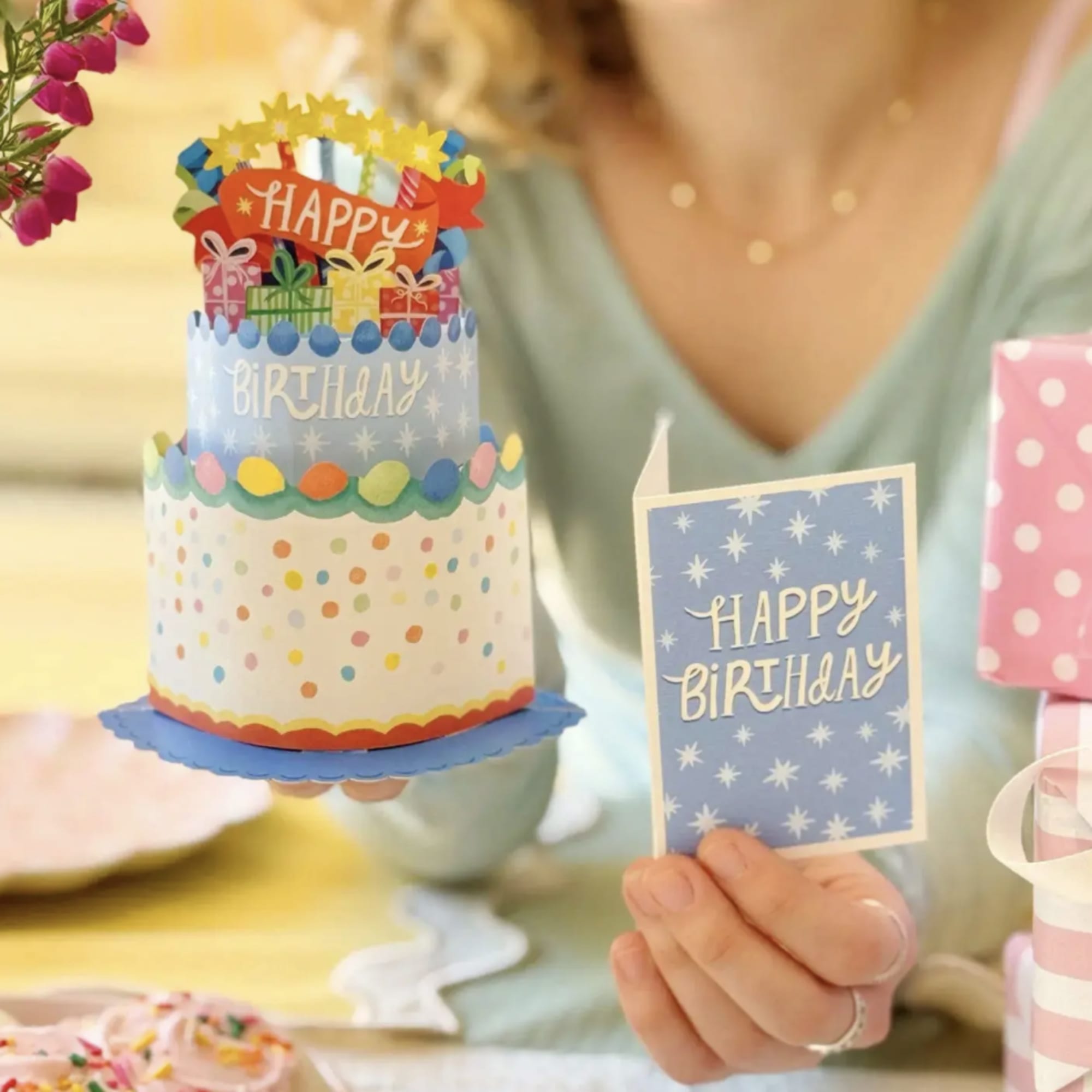 Birthday card and paper cake decoration held by a person