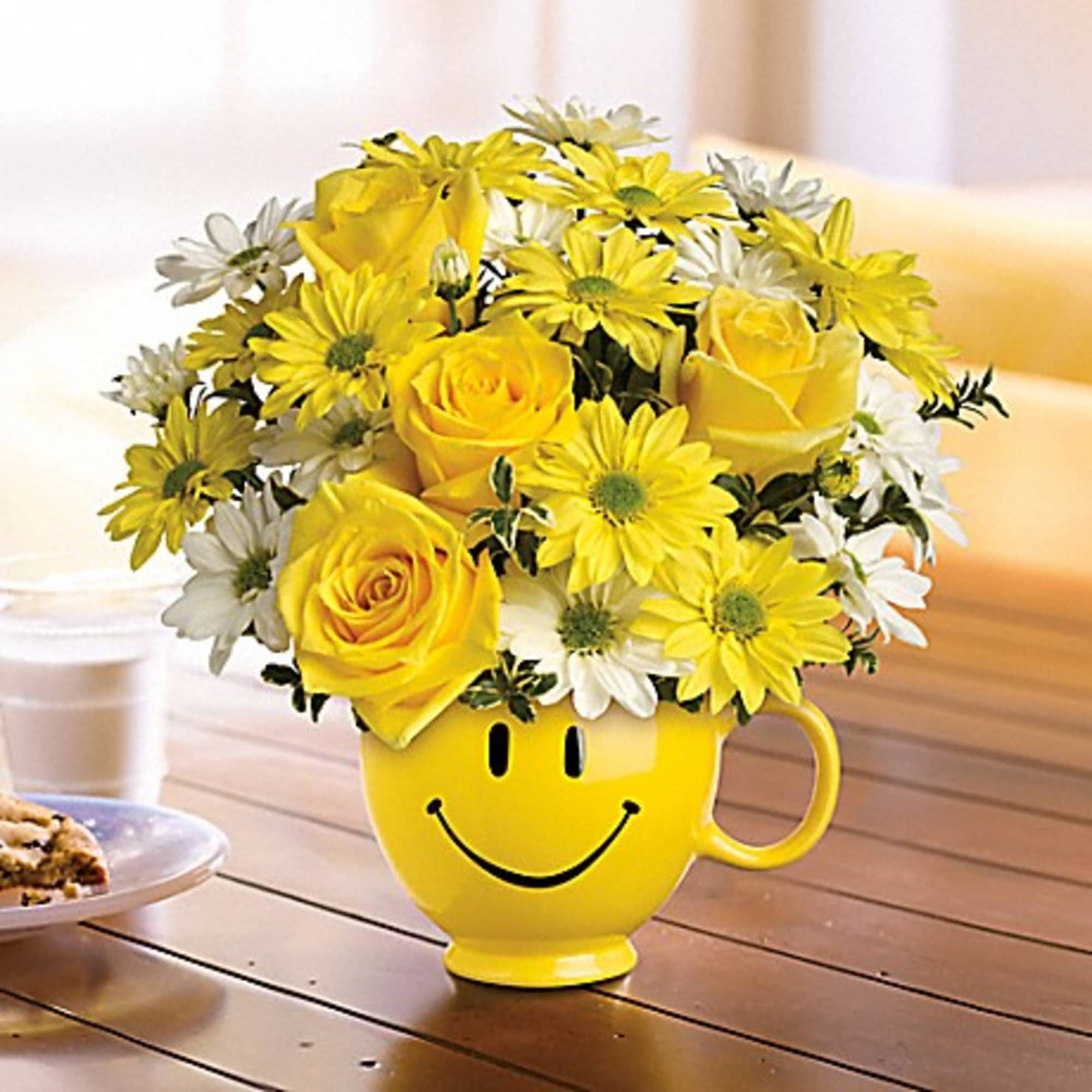 Yellow and white flowers arranged in a smiley-face mug