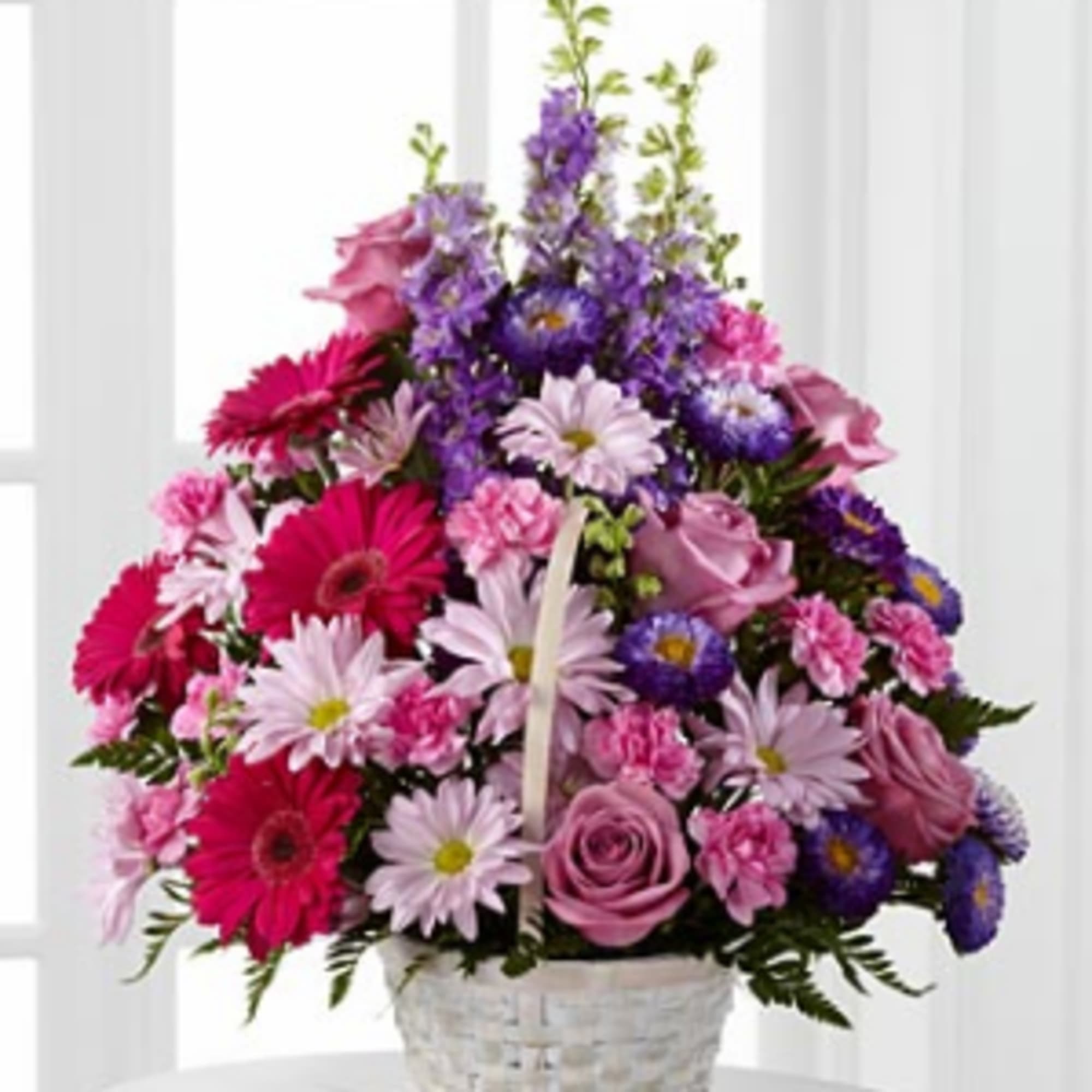 Pink and purple mixed flower arrangement in a white basket
