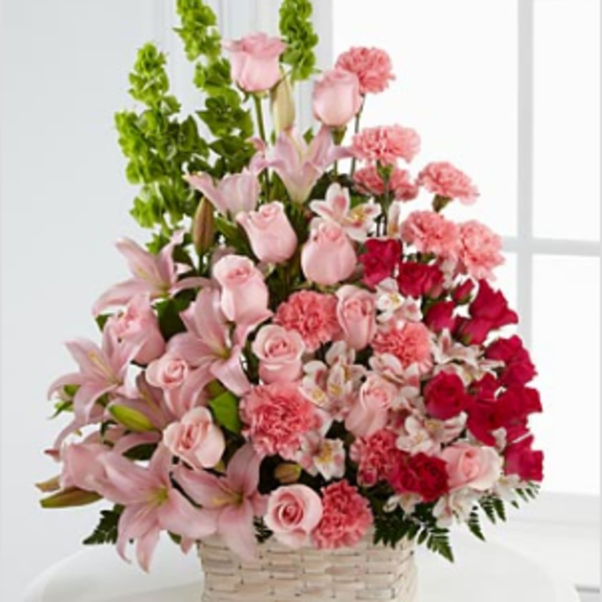 Pink mixed flower arrangement in a woven basket