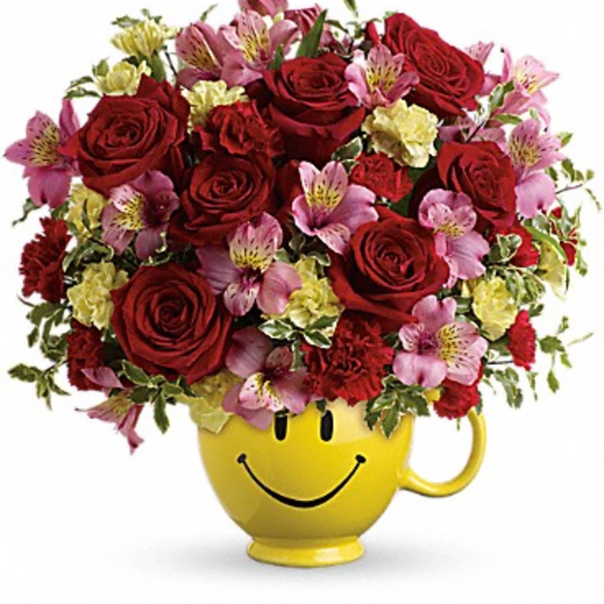 Bouquet of red roses and pink flowers in a yellow smiley-face mug
