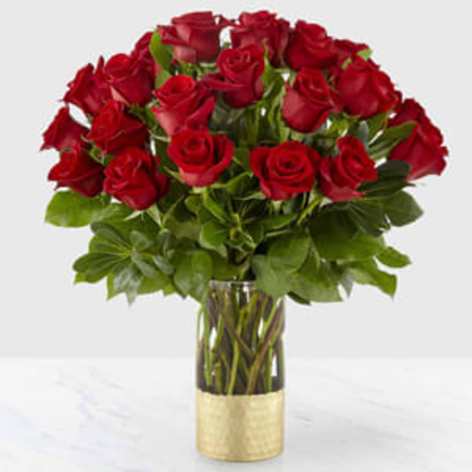 Bouquet of red roses in a clear glass vase with a gold base